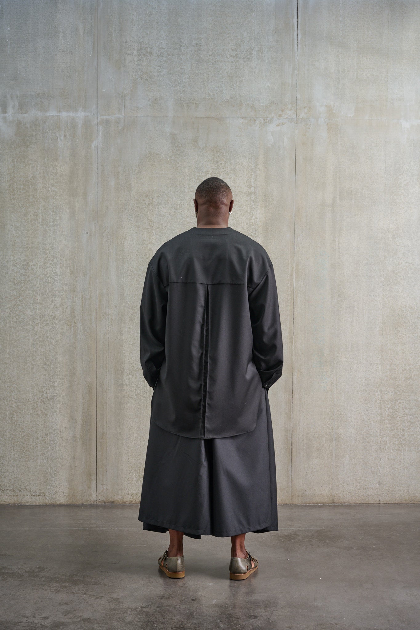 Jupe culotte oversize de la marque Aïdama, modèle Hakama en laine froide noire, portée par un modèle homme et vue de dos.