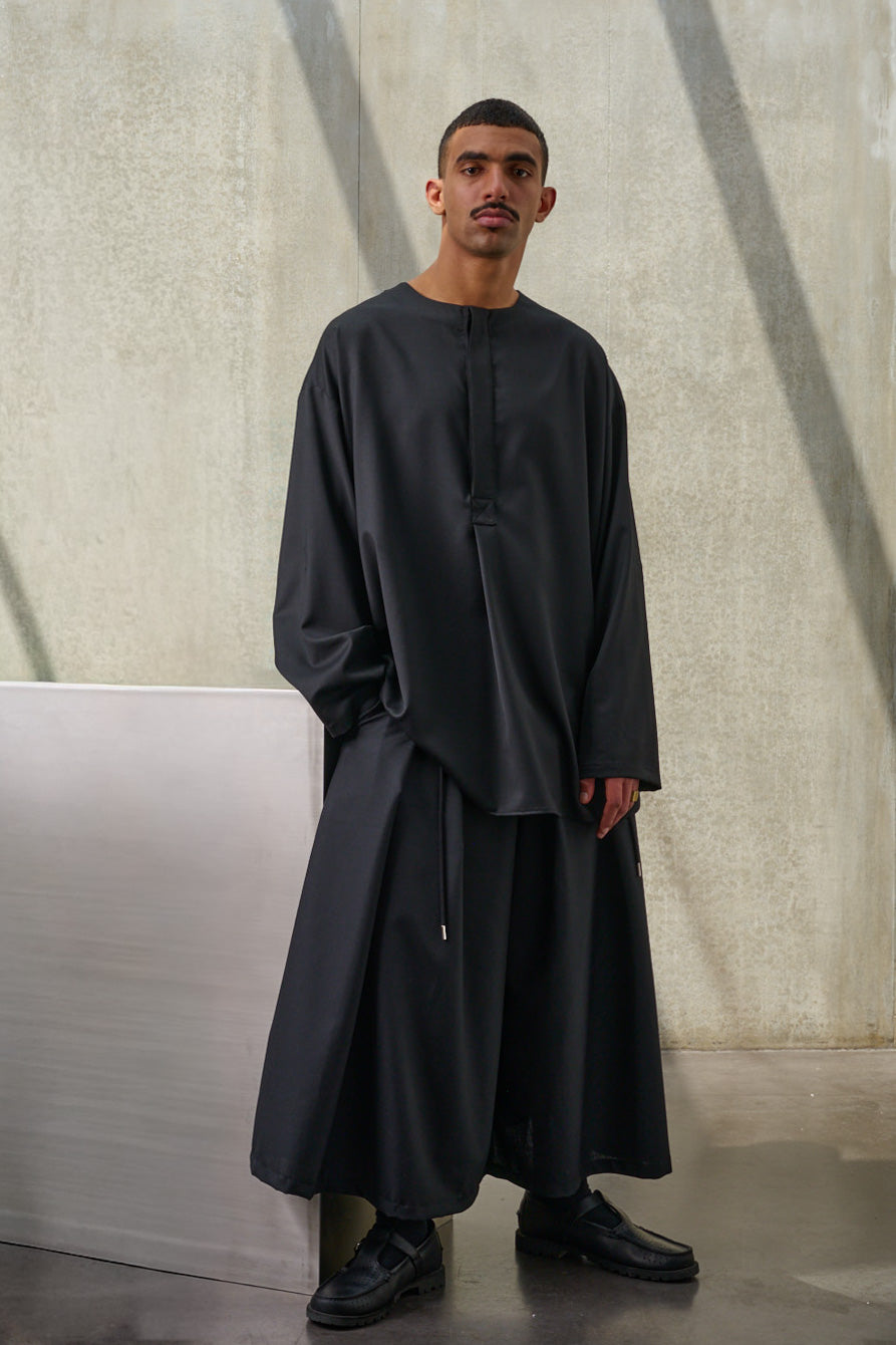 Jupe culotte oversize de la marque Aïdama, modèle Hakama en laine froide noire, portée par un modèle homme et vue de face.