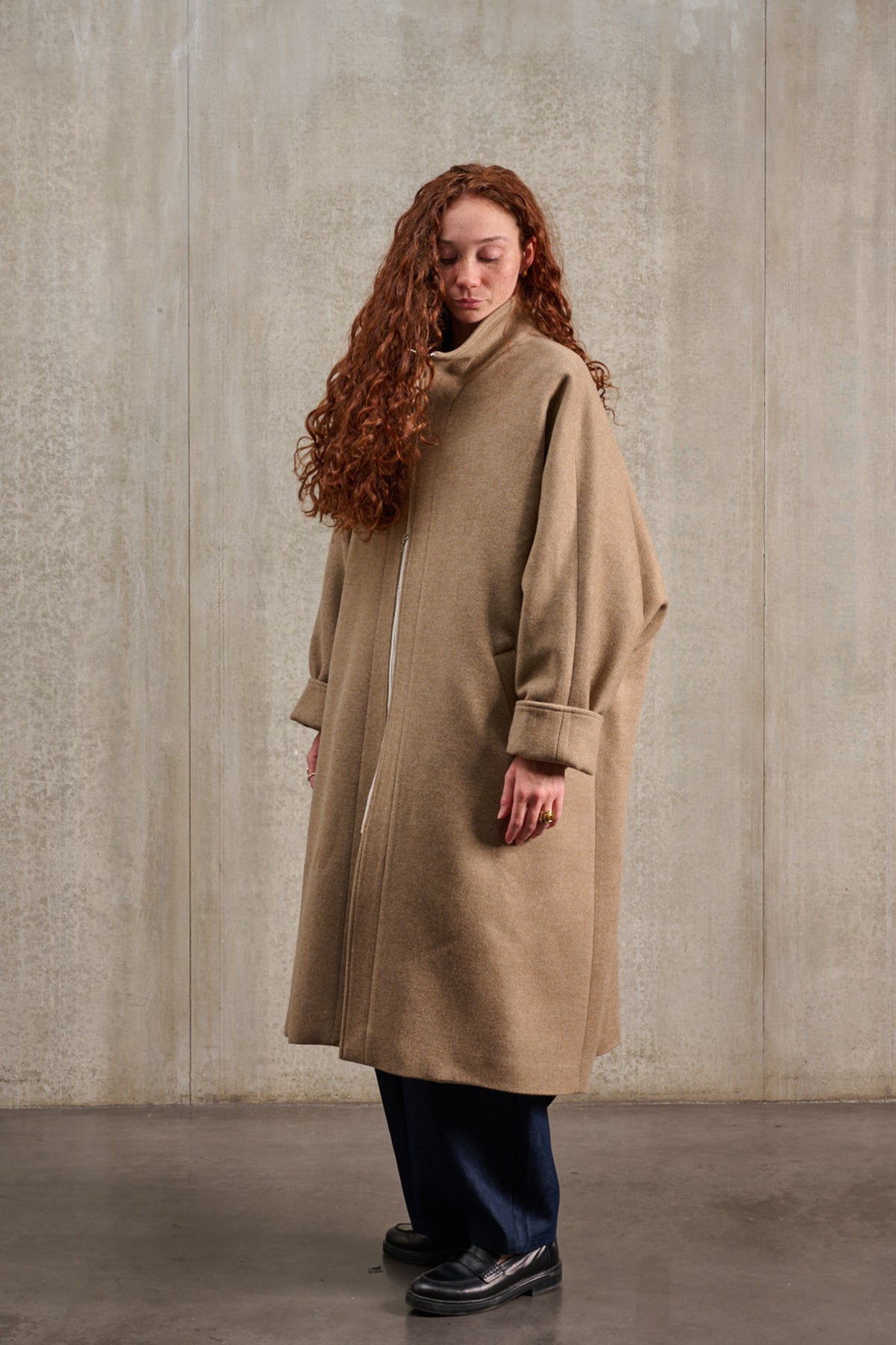 Manteau oversize à manches dolmans de la marque Aïdama, modèle Tanzen en laine et cachemire beige. Porté fermé par une mannequin femme et vu de trois quarts.