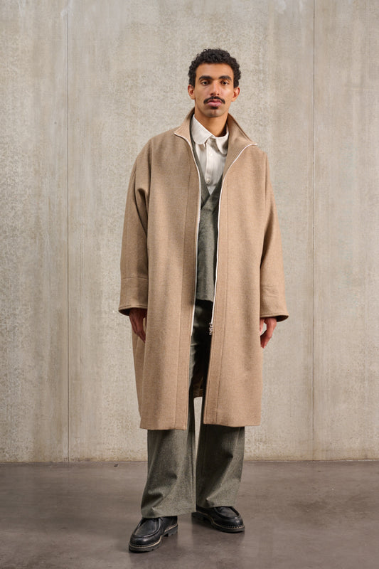 Manteau oversize à manches dolmans de la marque Aïdama, modèle Tanzen en laine et cachemire beige. Porté ouvert par un mannequin homme et vu de face.