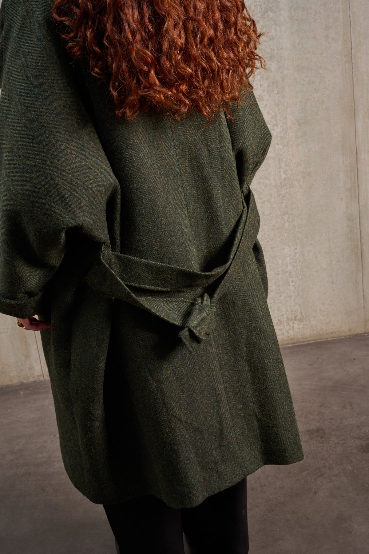 Manteau oversize à manches dolmans de la marque Aïdama, modèle Tanzen en laine, vert à motif chevrons. Porté ouvert par une mannequin femme et vu de dos.
