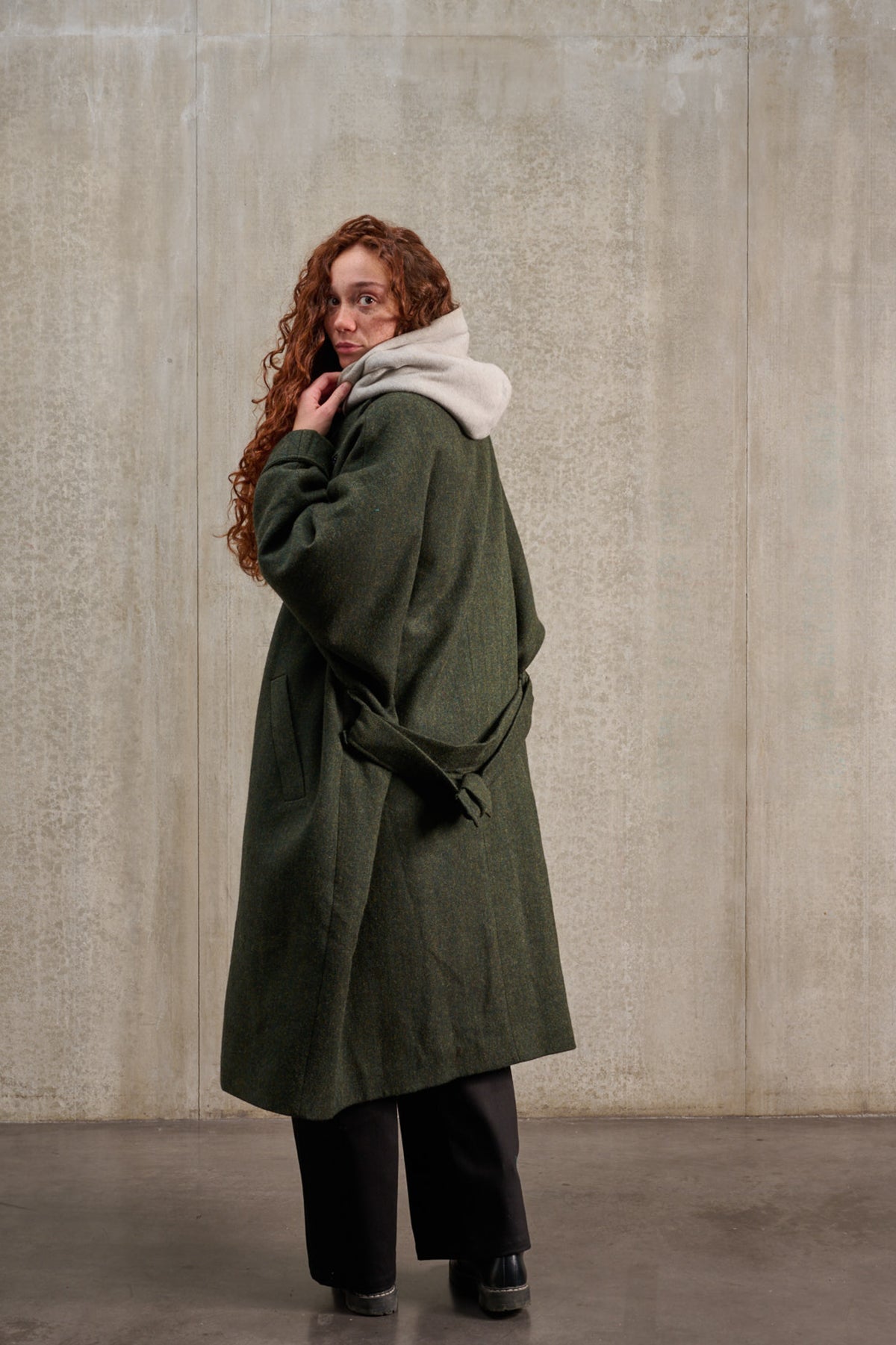Manteau oversize à manches dolmans de la marque Aïdama, modèle Tanzen en laine, vert à motif chevrons. Porté ouvert par une mannequin femme et vu de dos.