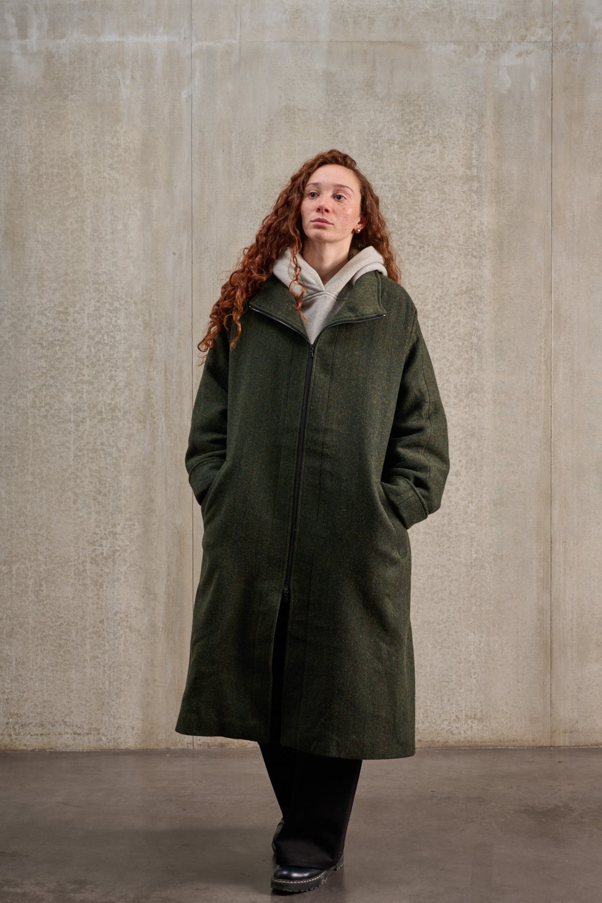 Manteau oversize à manches dolmans de la marque Aïdama, modèle Tanzen en laine, vert à motif chevrons. Porté fermé par une mannequin femme et vu de face.