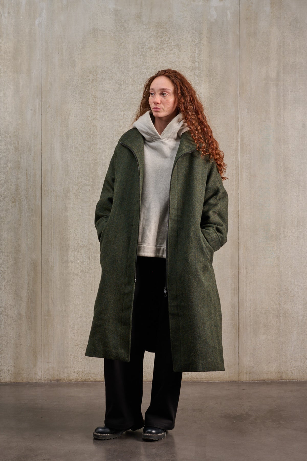 Manteau oversize à manches dolmans de la marque Aïdama, modèle Tanzen en laine, vert à motif chevrons. Porté ouvert par une mannequin femme et vu de trois quarts.