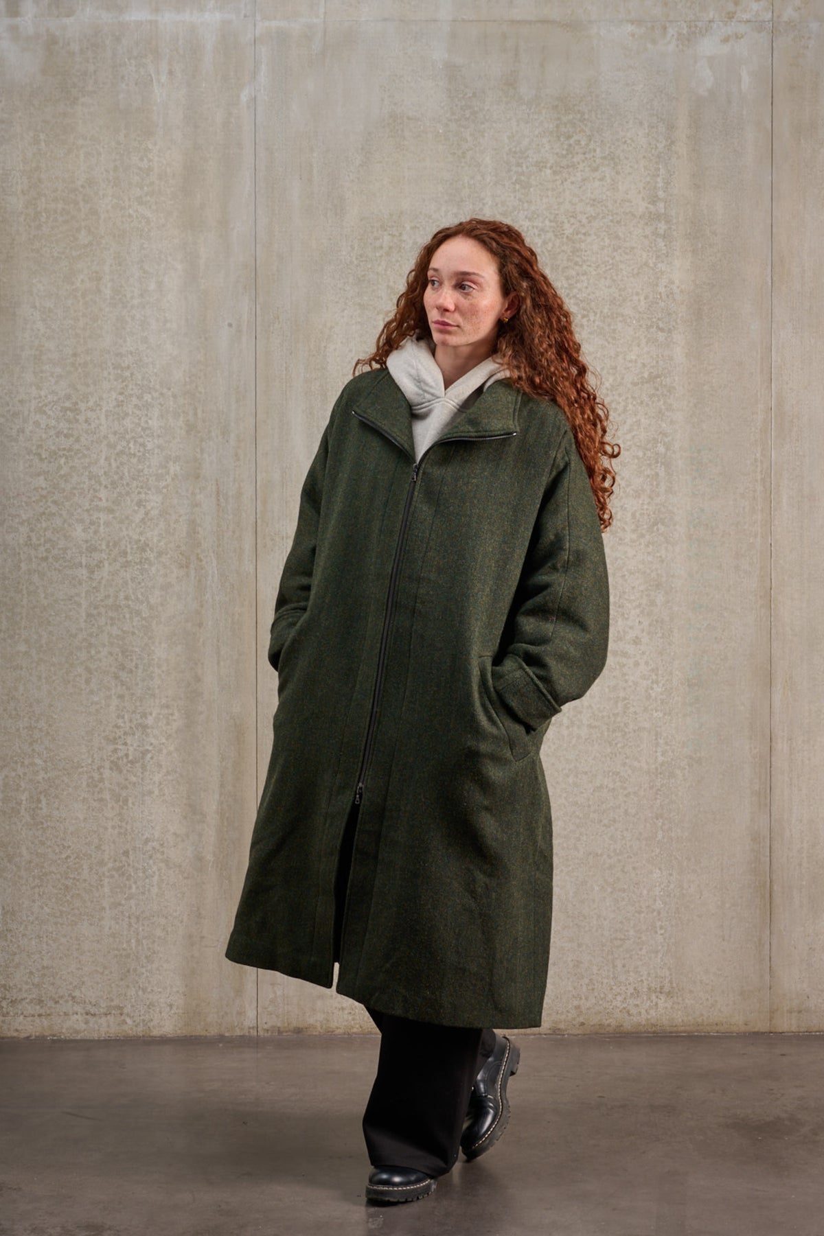 Manteau oversize à manches dolmans de la marque Aïdama, modèle Tanzen en laine, vert à motif chevrons. Porté fermé par une mannequin femme et vu centré sur de trois quarts.