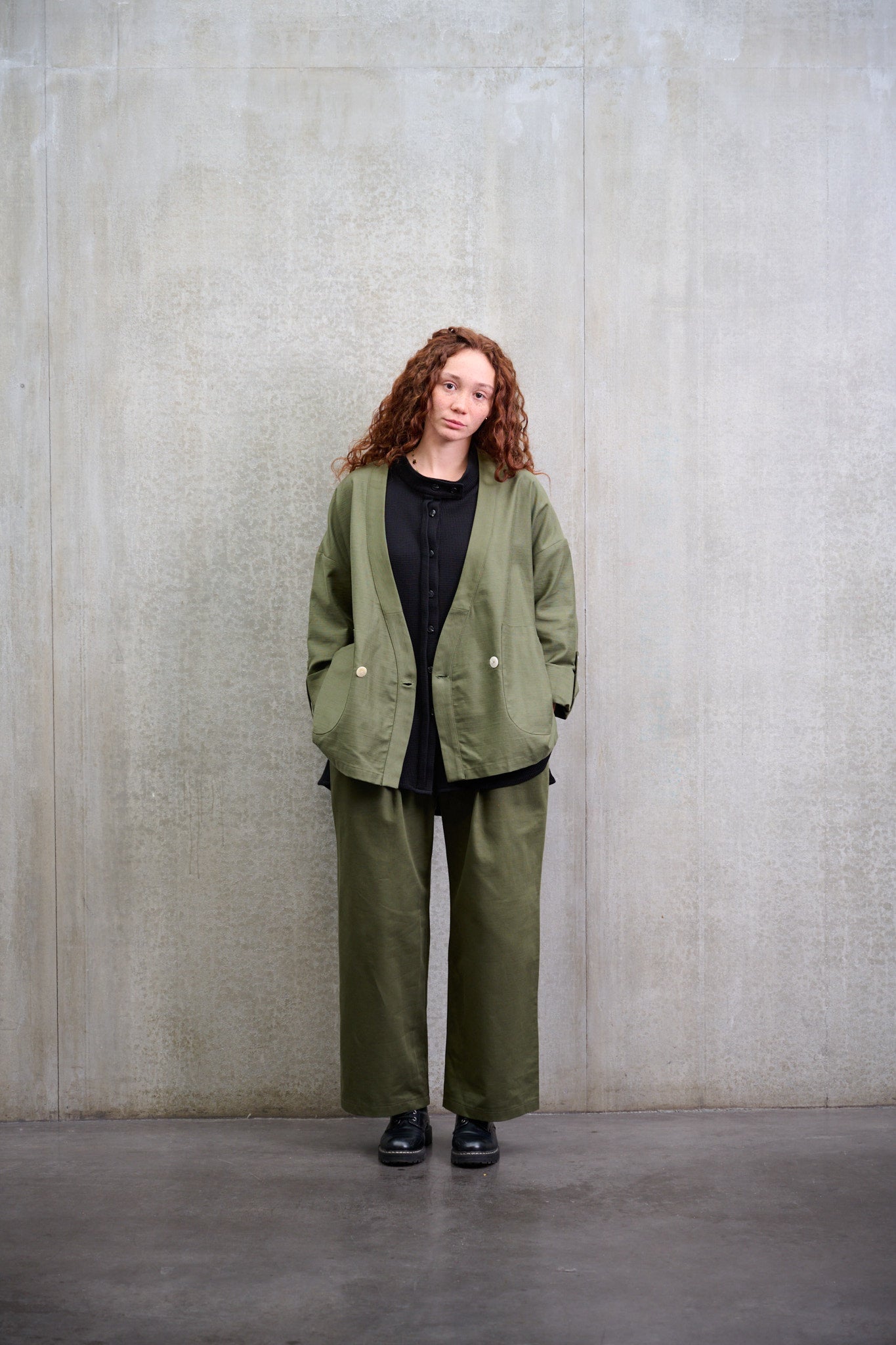 Pantalon droit à coupe ample de la marque Aïdama, avec sangles de réglages, en coton vert. Porté par une mannequin femme et vu de face.