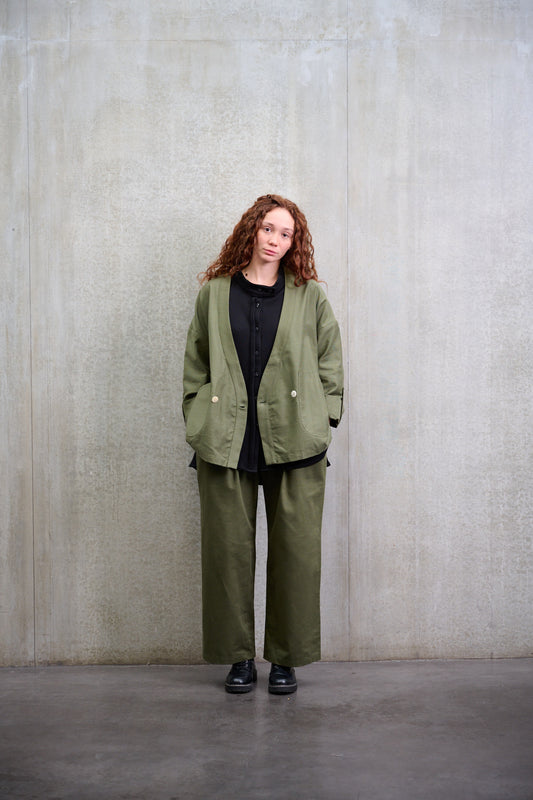 Pantalon droit à coupe ample de la marque Aïdama, avec sangles de réglages, en coton vert. Porté par une mannequin femme et vu de face.