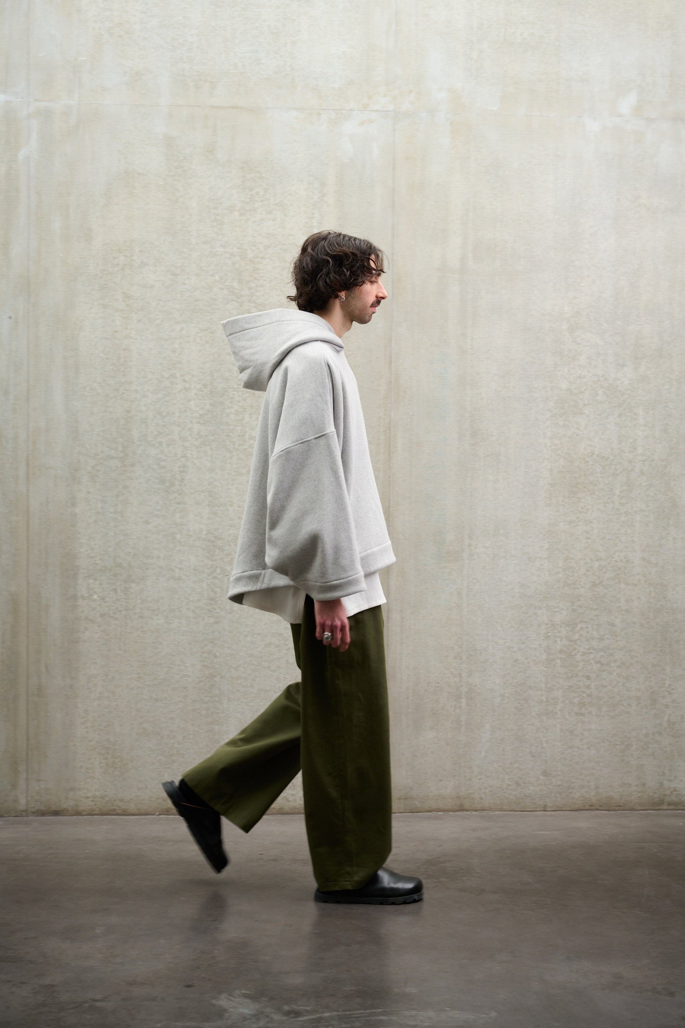 Pantalon droit à coupe ample en coton vert avec sangles de réglages de la marque Aïdama. Porté par un mannequin homme et vue de profil en mouvement de marche.