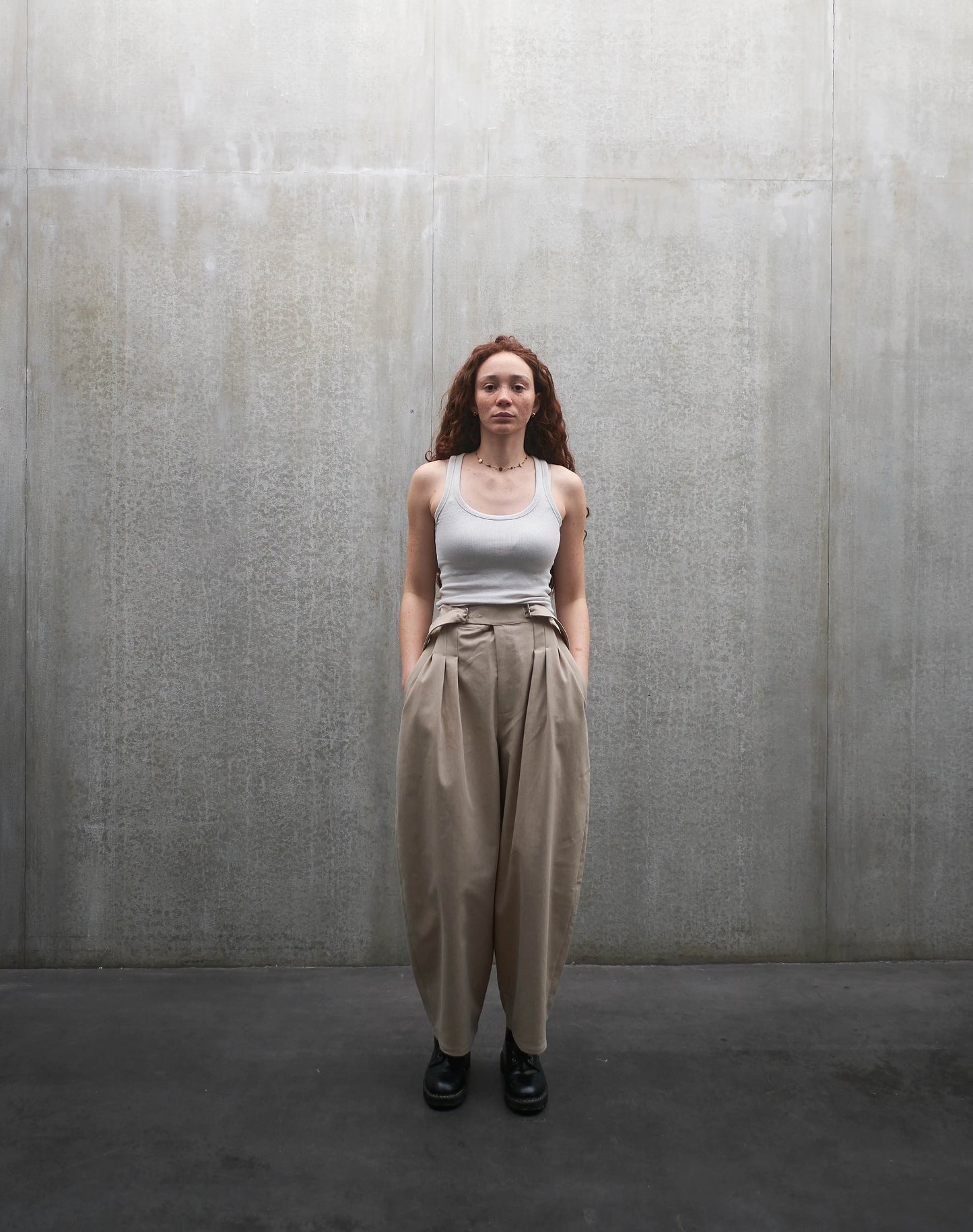 Pantalon circulaire Aïdama, coupe ballon en coton beige. Porté par une mannequin femme et vu de face.