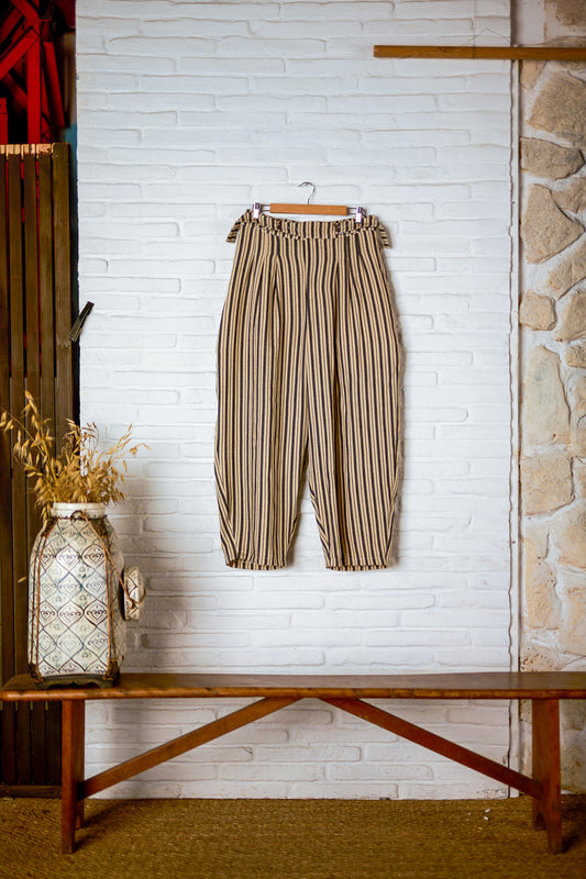 Pantalon circulaire de la marque Aïdama, coupe ballon en coton crème à rayures noires. Vu sur ceintre contre un mur blanc.