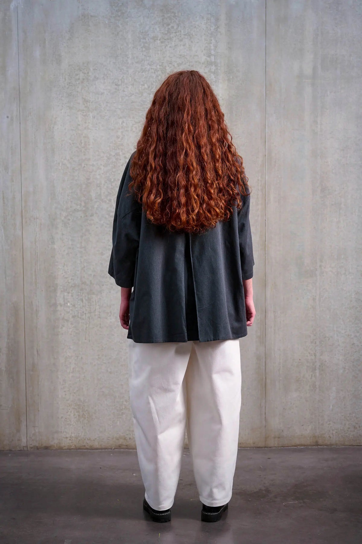 Pantalon circulaire unisexe de la marque Aïdama, coupe ballon en sergé de coton blanc. Porté par une mannequin femme et vu de dos.
