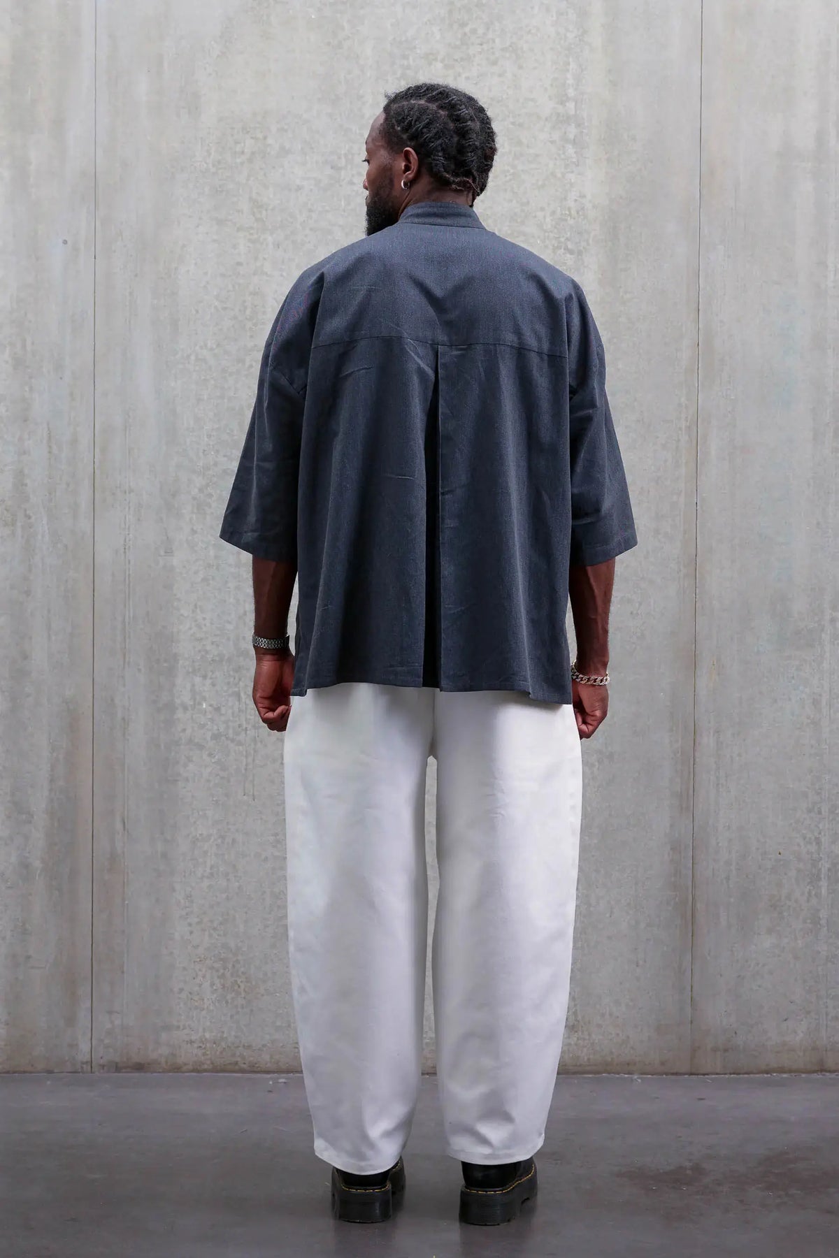 Pantalon circulaire unisexe de la marque Aïdama, coupe ballon en sergé de coton blanc. Porté par un mannequin homme et vu de dos.