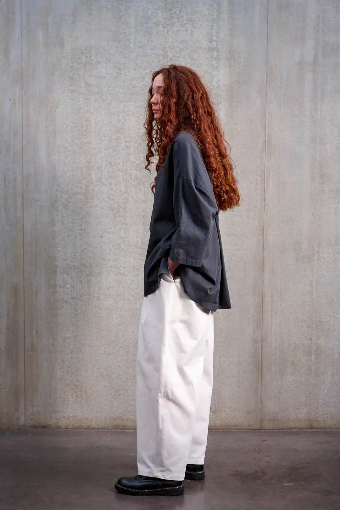 Pantalon circulaire unisexe de la marque Aïdama, coupe ballon en sergé de coton blanc. Porté par une mannequin femme et vu de profil.