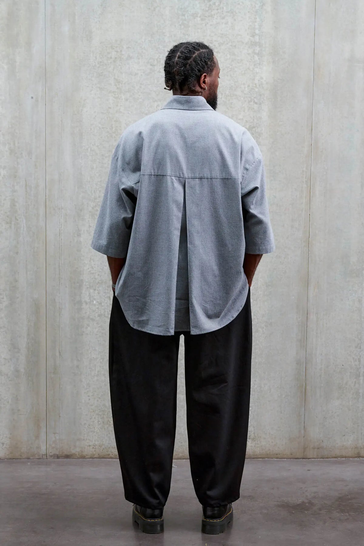 Pantalon circulaire unisexe de la marque Aïdama, coupe ballon en sergé de coton noir. Porté par un mannequin homme et vu de dos.