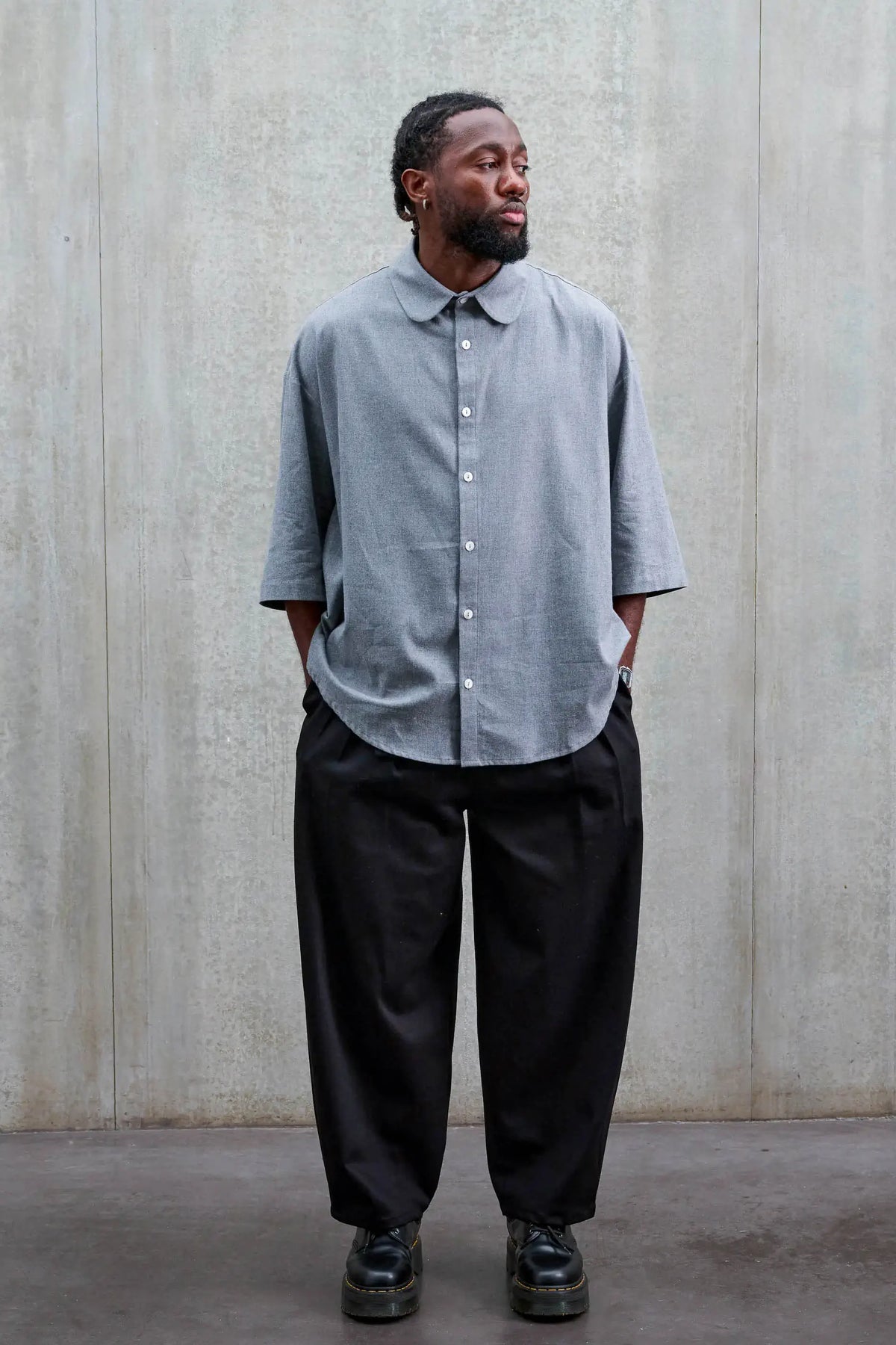 Pantalon circulaire unisexe de la marque Aïdama, coupe ballon en sergé de coton noir. Porté par un mannequin homme et vu de face.