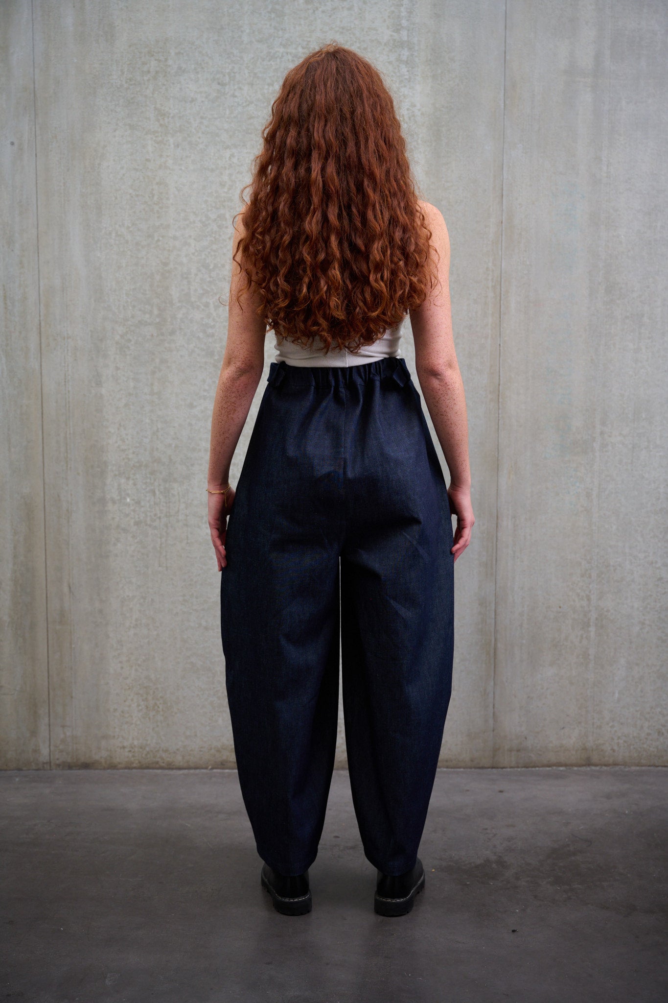 Pantalon circulaire Aïdama coupe ballon en denim brut. Porté par une mannequin  femme et vu de dos.