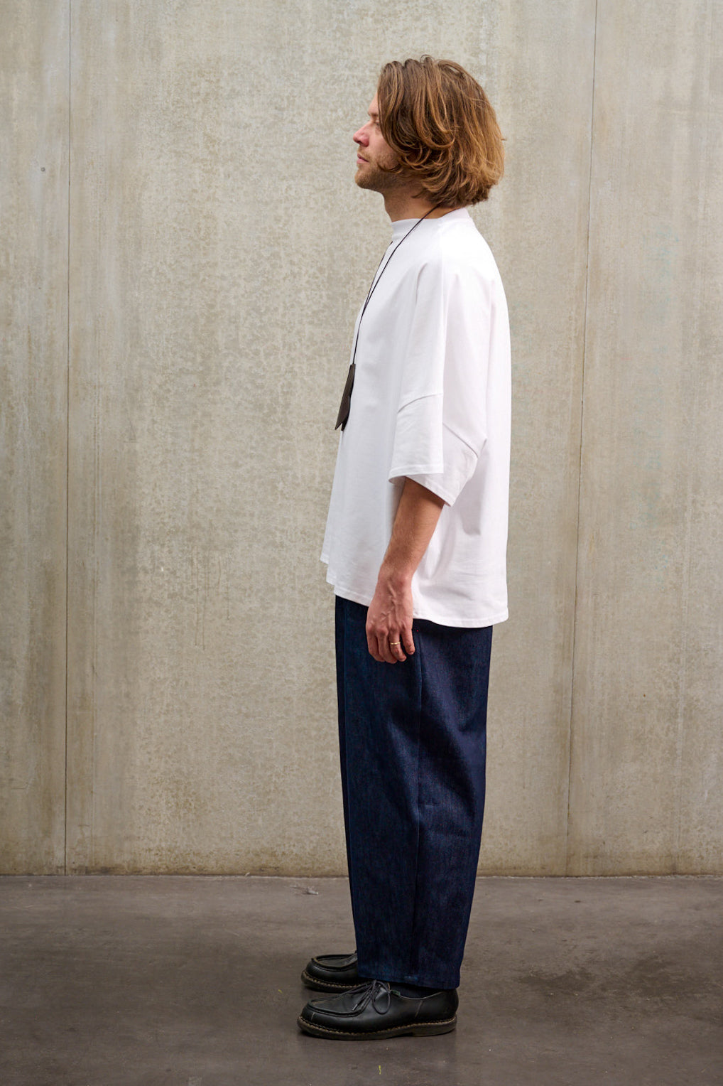 Pantalon circulaire Aïdama coupe ballon en denim brut. Porté par un mannequin homme et vu de profil.