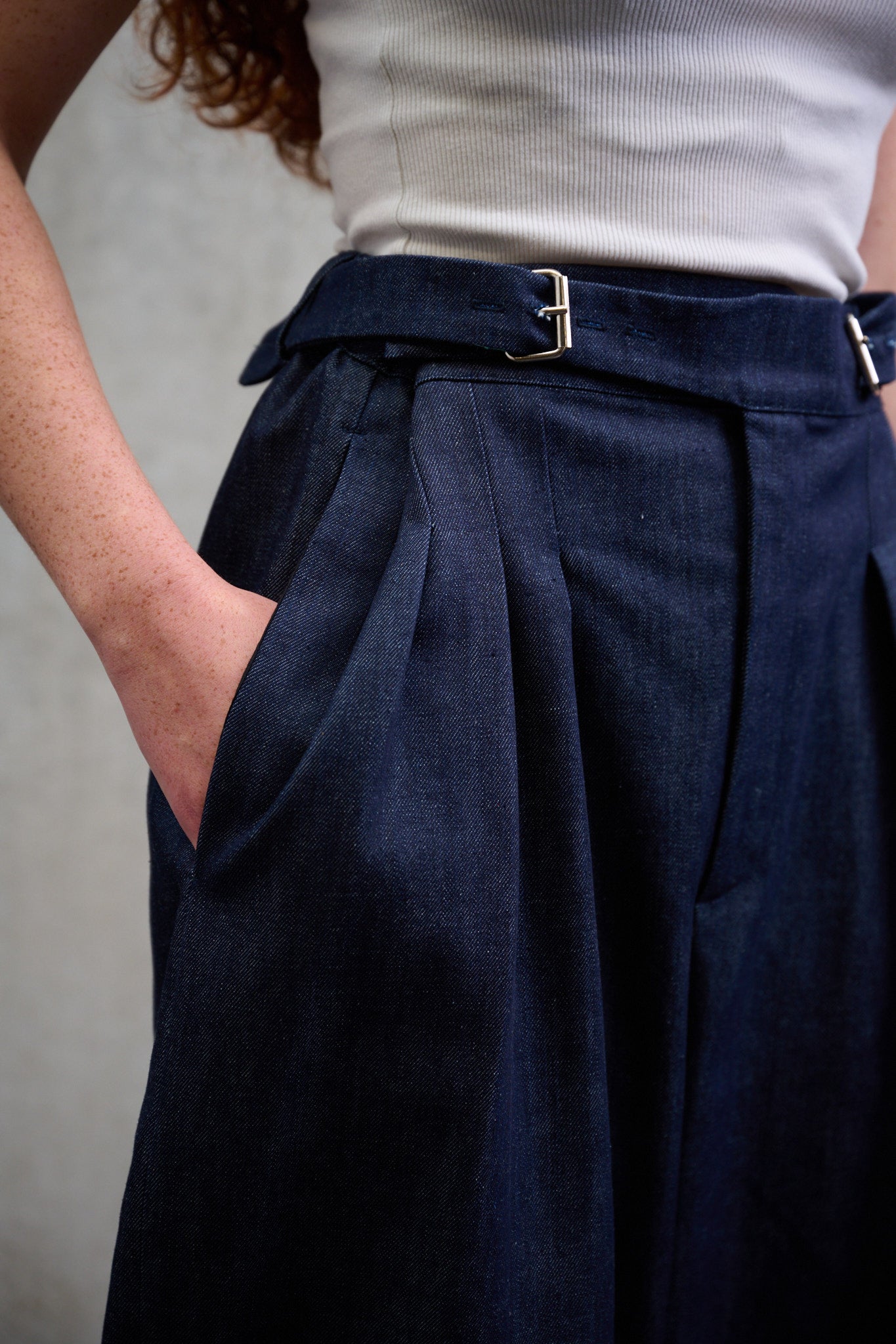 Pantalon circulaire Aïdama coupe ballon en denim brut. Porté par une mannequin femme, vue zoomée sur la ceinture gurkha.