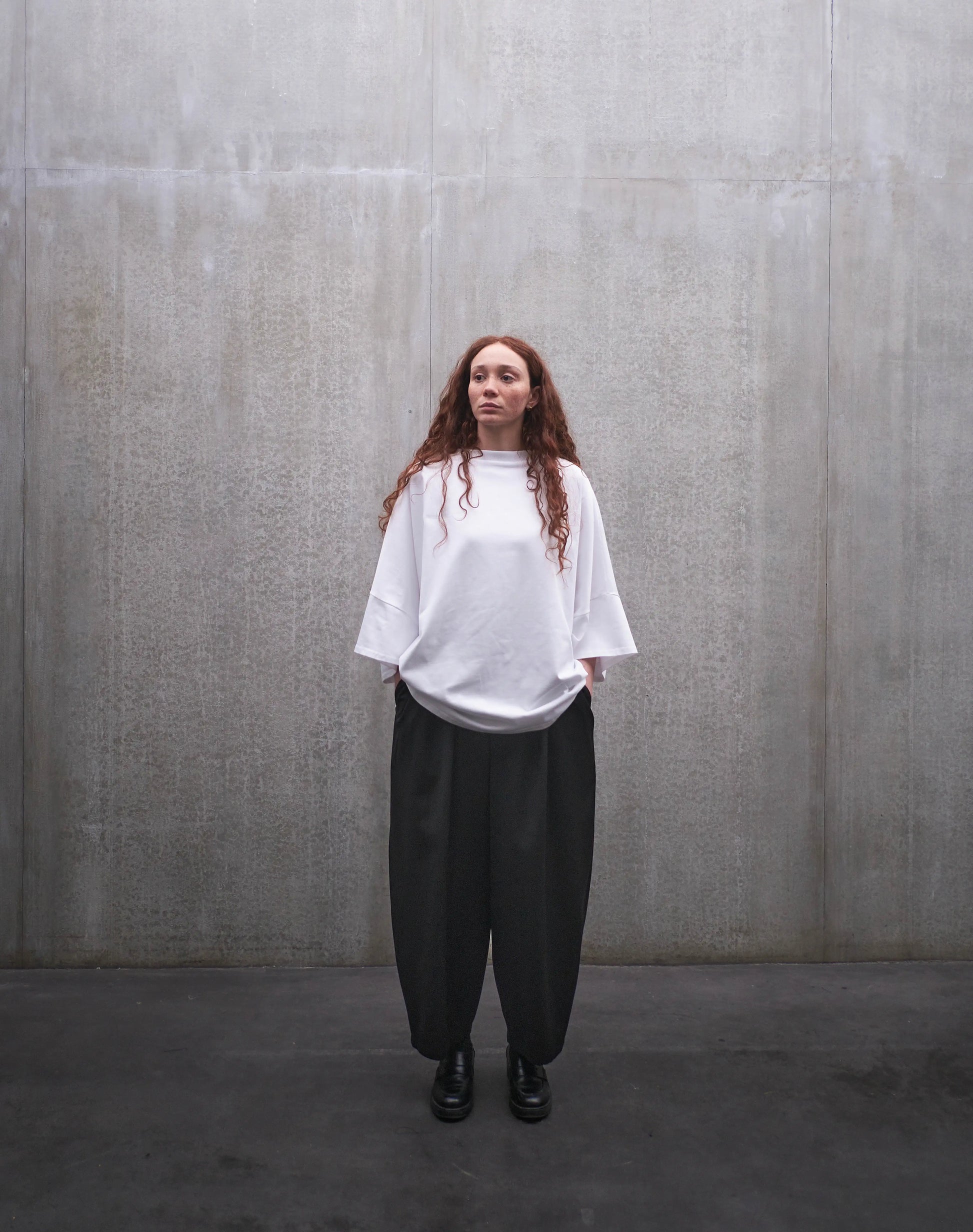 Pantalon circulaire Aïdama, coupe ballon en laine froide noire. Porté par une mannequin femme et vu de face.