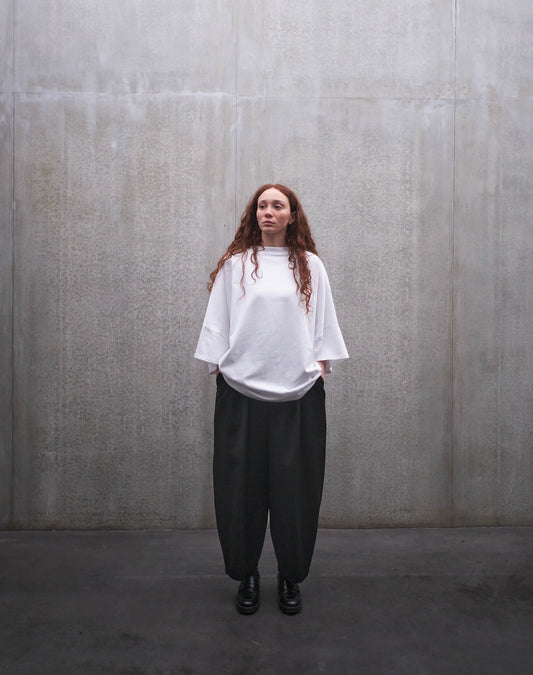 Pantalon circulaire Aïdama, coupe ballon en laine froide noire. Porté par une mannequin femme et vu de face.