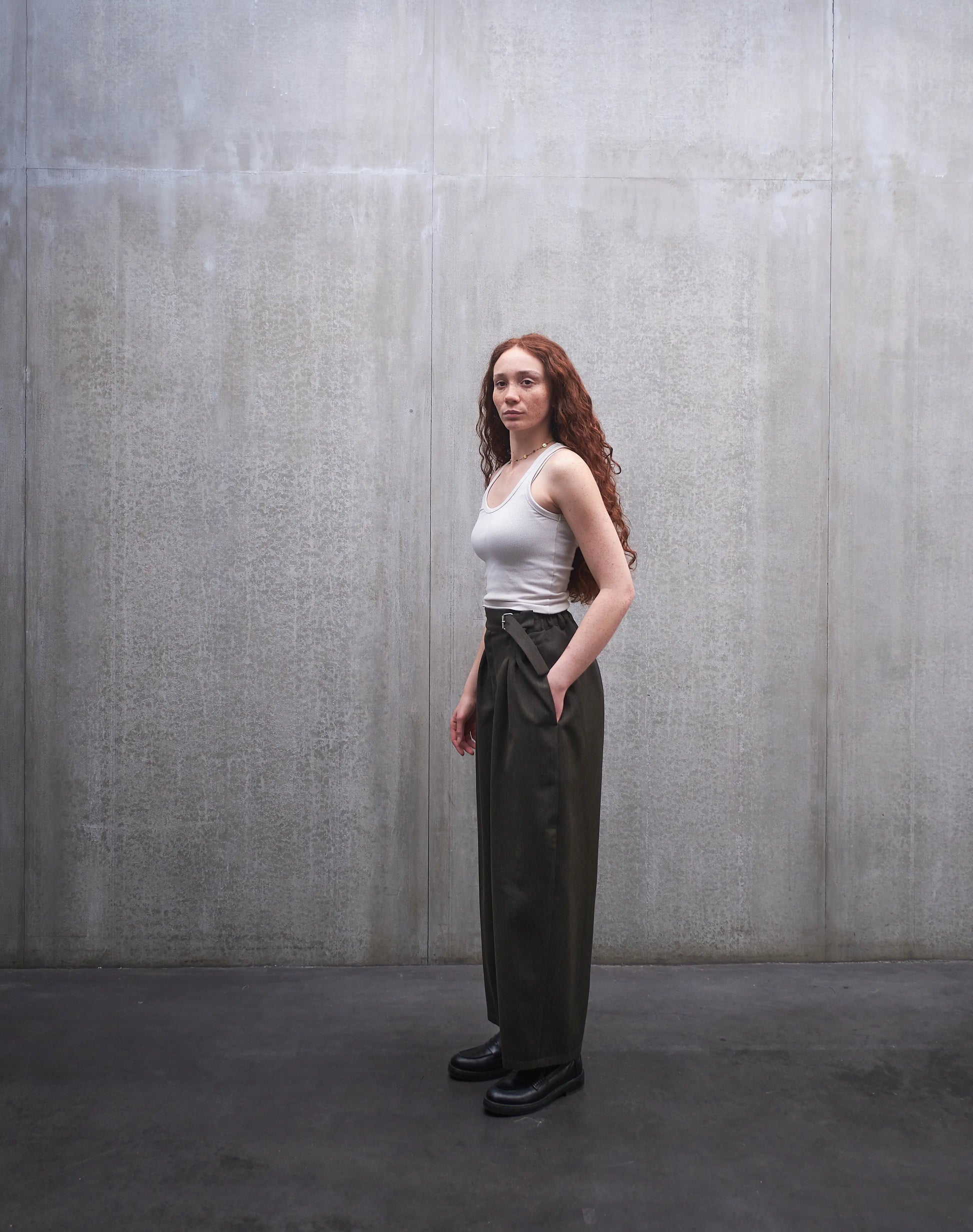 Pantalon circulaire Aïdama, coupe ballon en laine froide vert chiné. Porté par une mannequin femme et vu de profil.
