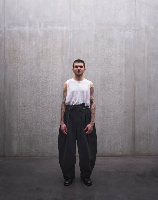 Pantalon circulaire Aïdama, coupe ballon en coton noir à motif Prince de Galles ton sur ton. Porté par un mannequin homme et vu de face.