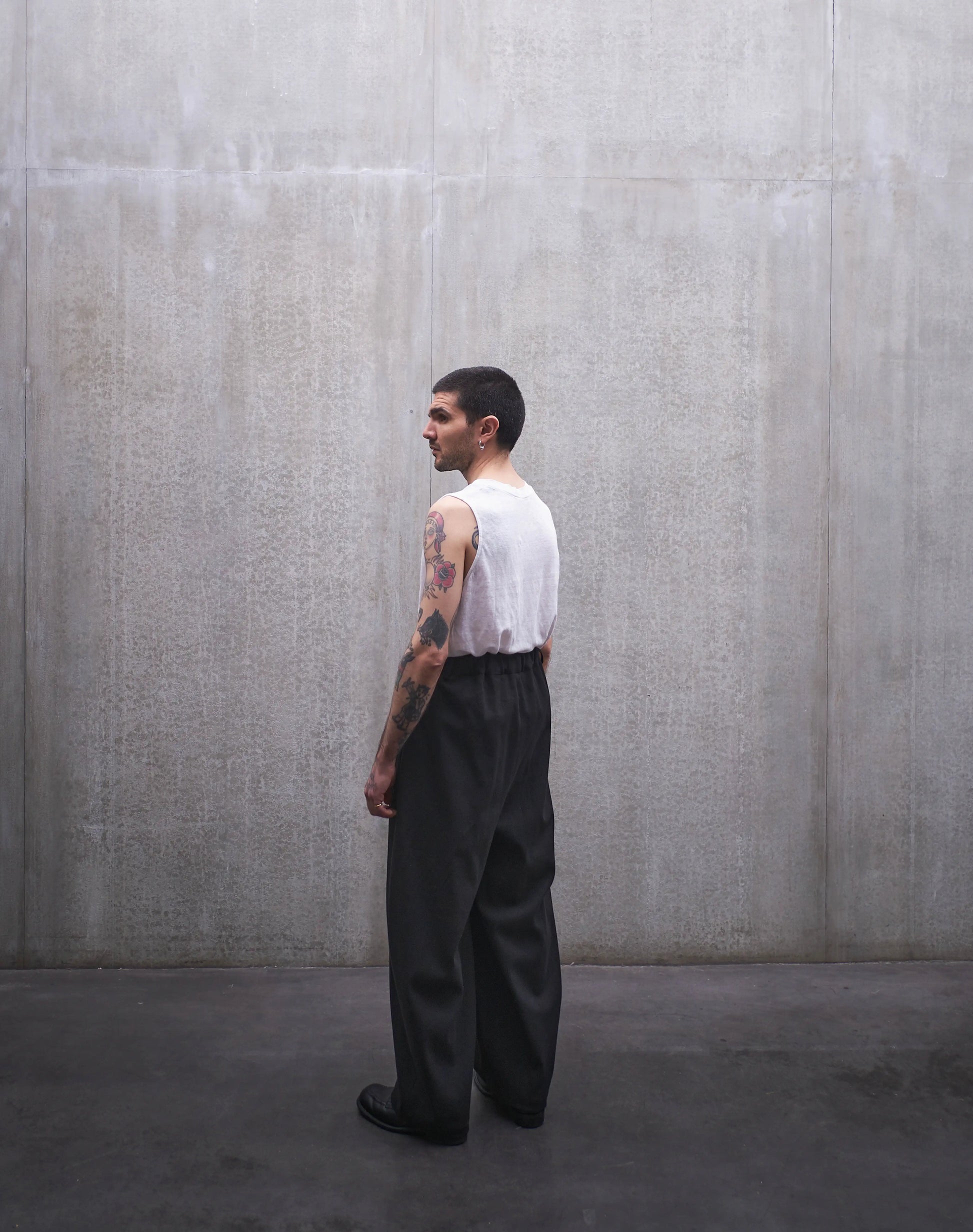 Pantalon circulaire Aïdama, coupe ballon en coton noir à motif Prince de Galles ton sur ton. Porté par un mannequin homme et vu de dos.