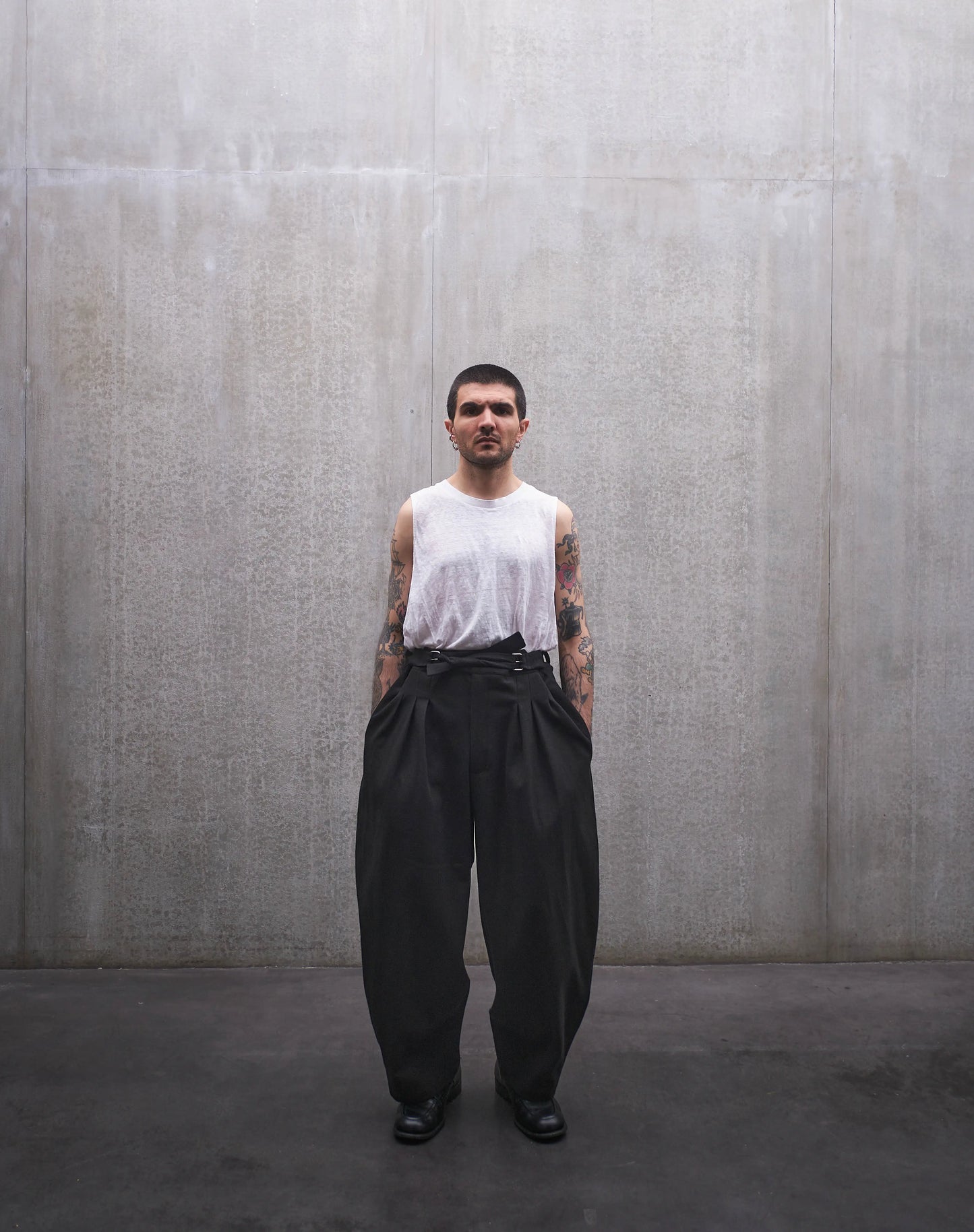 Pantalon circulaire Aïdama, coupe ballon en coton noir à motif Prince de Galles ton sur ton. Porté par un mannequin homme et vu de face.
