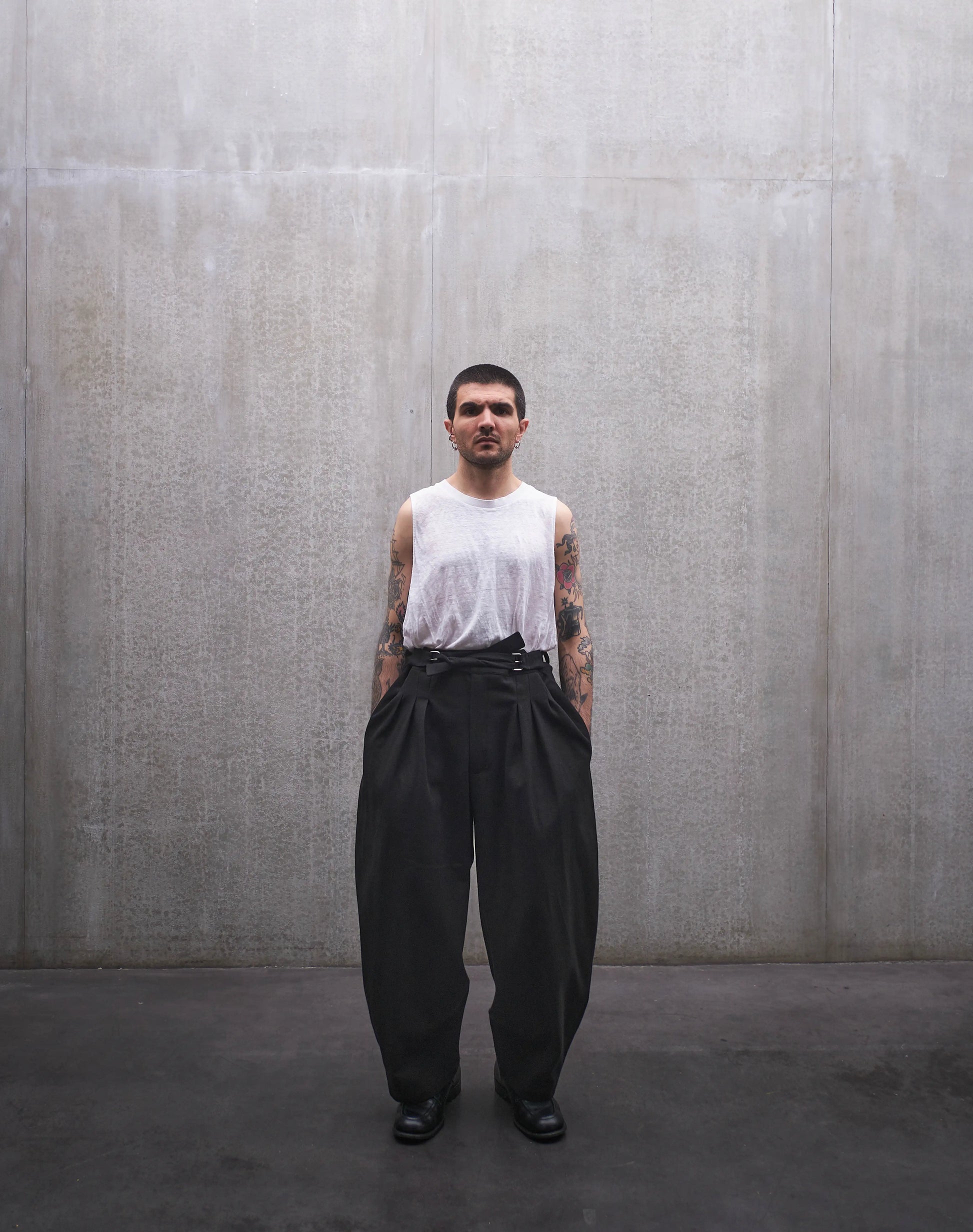 Pantalon circulaire Aïdama, coupe ballon en coton noir à motif Prince de Galles ton sur ton. Porté par un mannequin homme et vu de face.