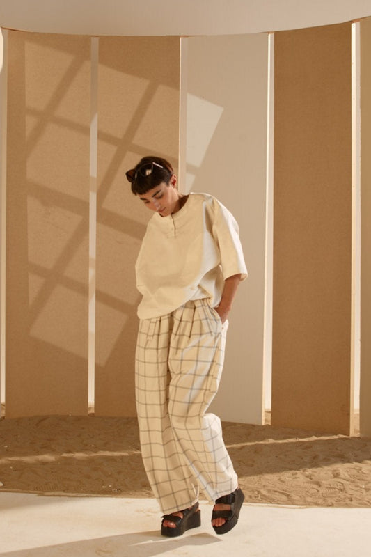Pantalon circulaire de la marque Aïdama, coupe ballon en coton crème à carreaux. Porté par une mannequin femme et vu de face. 