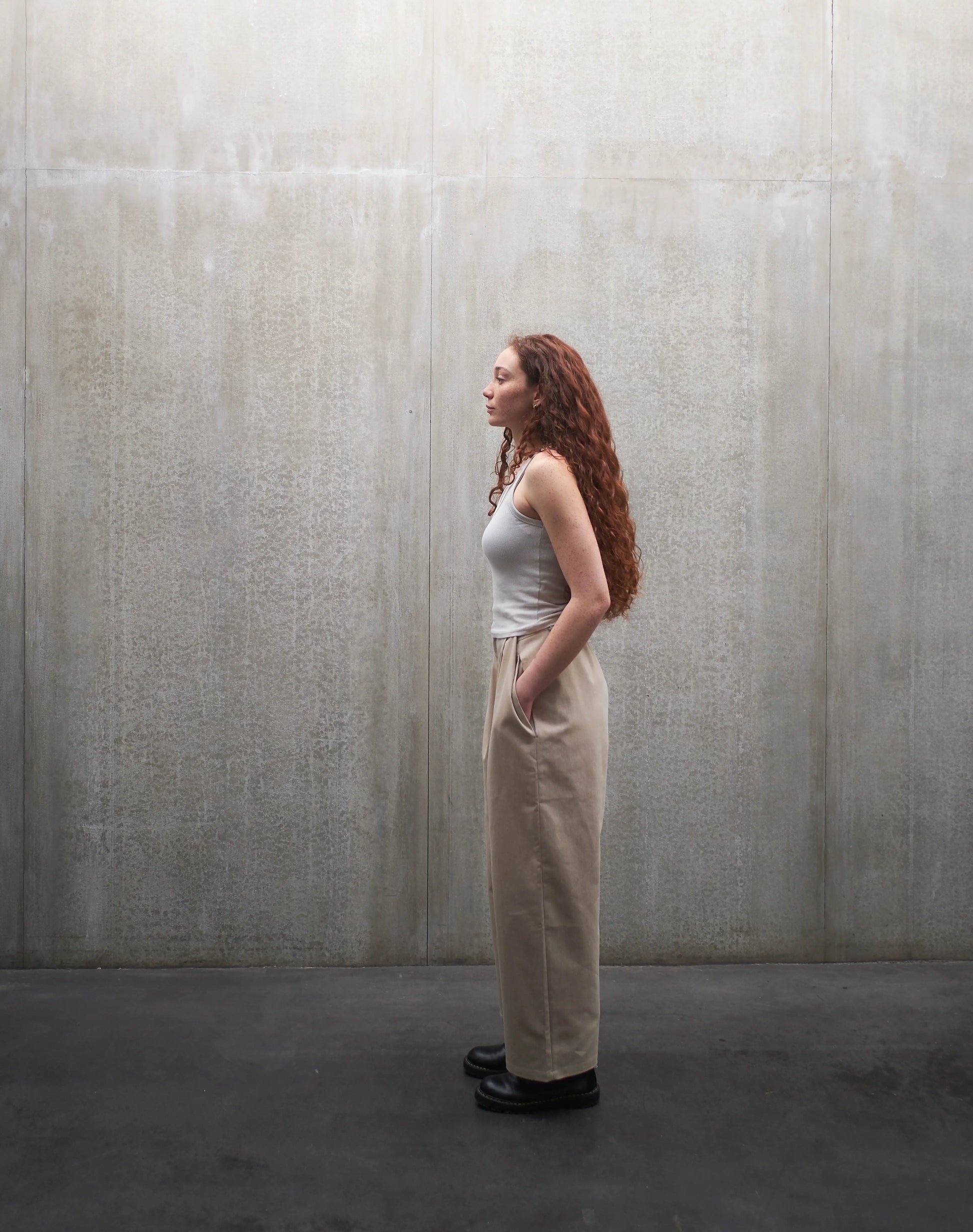 Pantalon droit Aïdama, coupe oversize en coton beige. Porté par une mannequin femme et vu de profil.