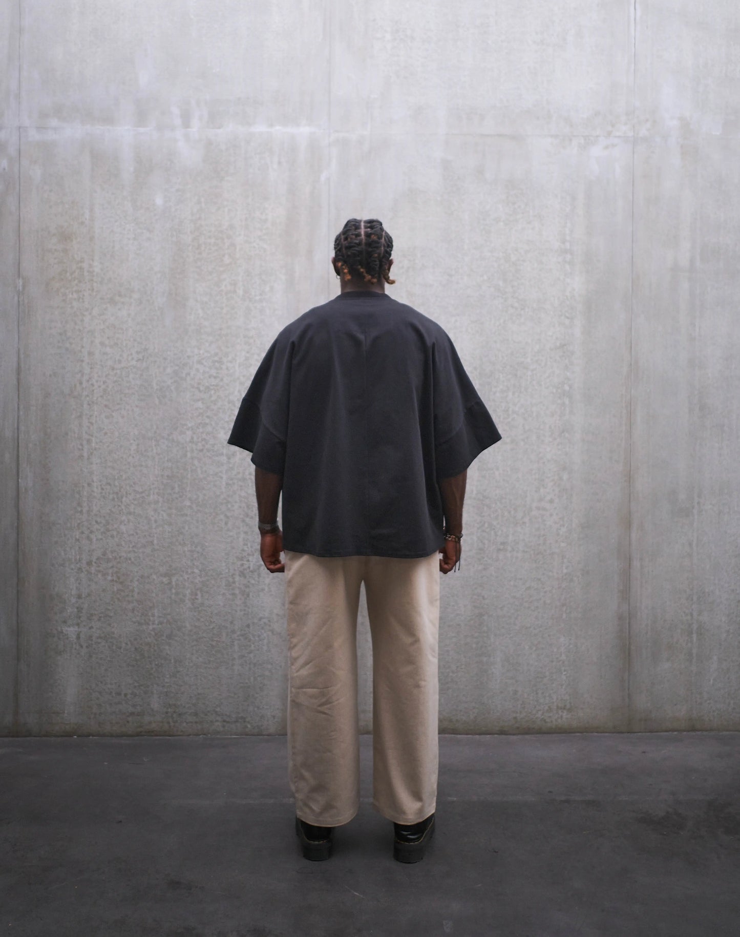 Pantalon droit Aïdama, coupe oversize en coton beige. Porté par un mannequin homme et vu de dos.