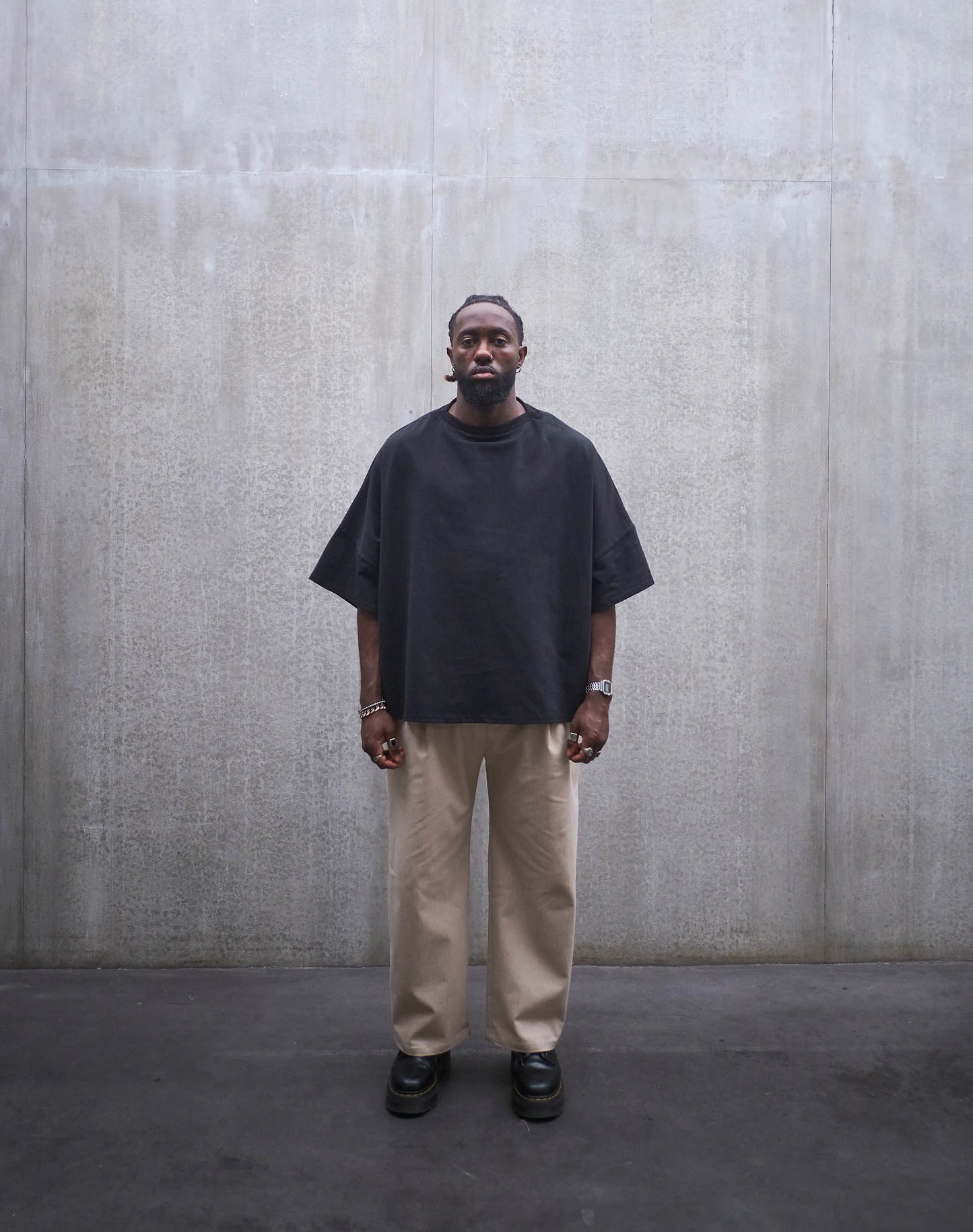 Pantalon droit Aïdama, coupe oversize en coton beige. Porté par un mannequin homme et vu de face.
