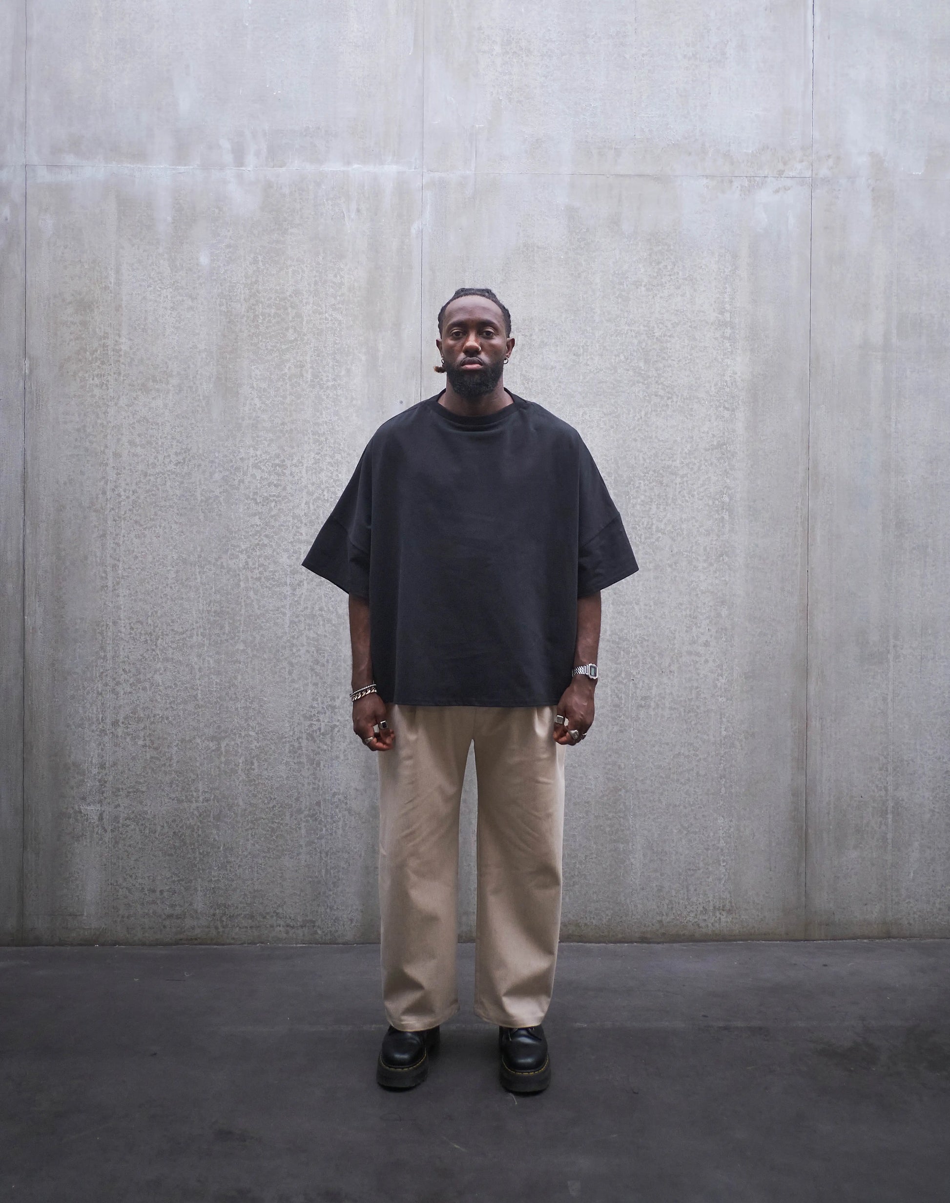 Pantalon droit Aïdama, coupe oversize en coton beige. Porté par un mannequin homme et vu de face.
