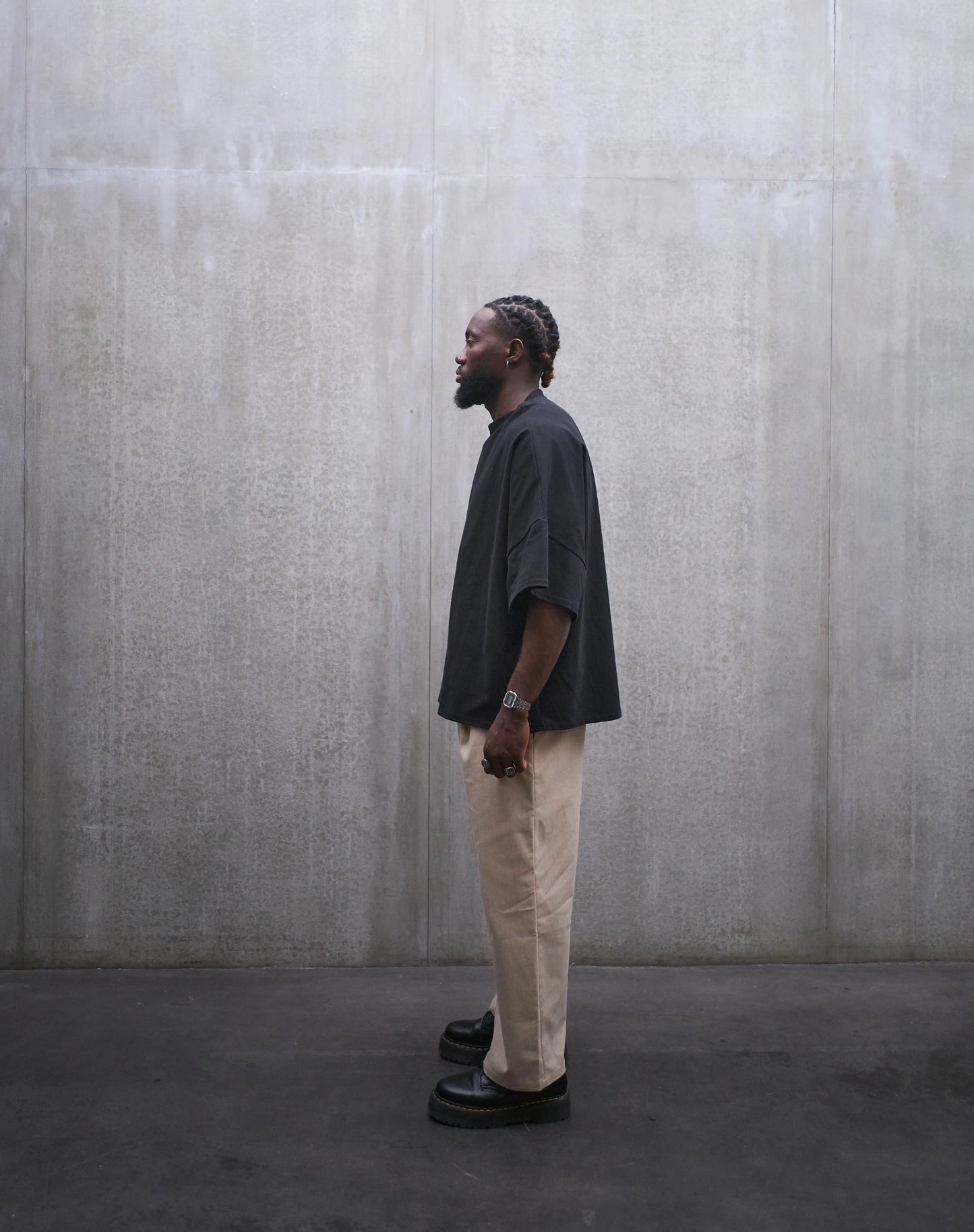 Pantalon droit Aïdama, coupe oversize en coton beige. Porté par un mannequin homme et vu de profil.