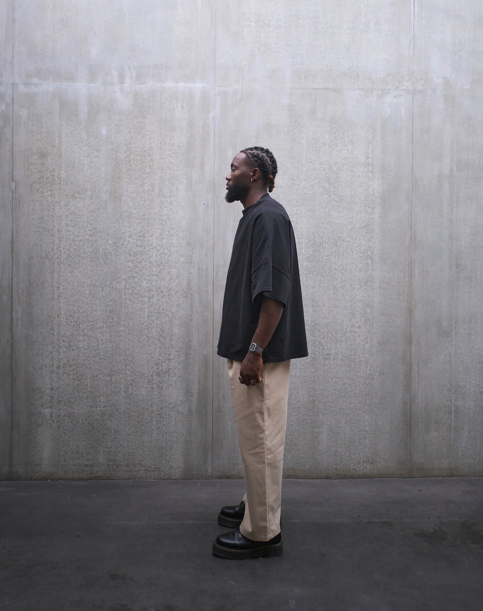 Pantalon droit Aïdama, coupe oversize en coton beige. Porté par un mannequin homme et vu de profil.
