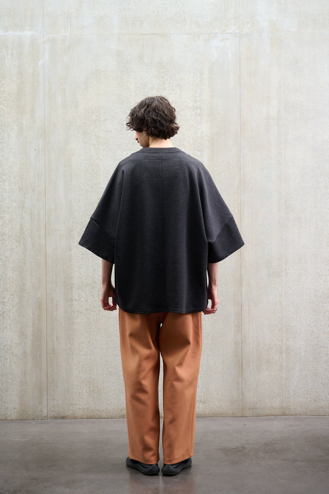 Pantalon droit de la marque Aïdama coupe oversize en laine et coton orange. Porté par un mannequin homme, vu de dos.