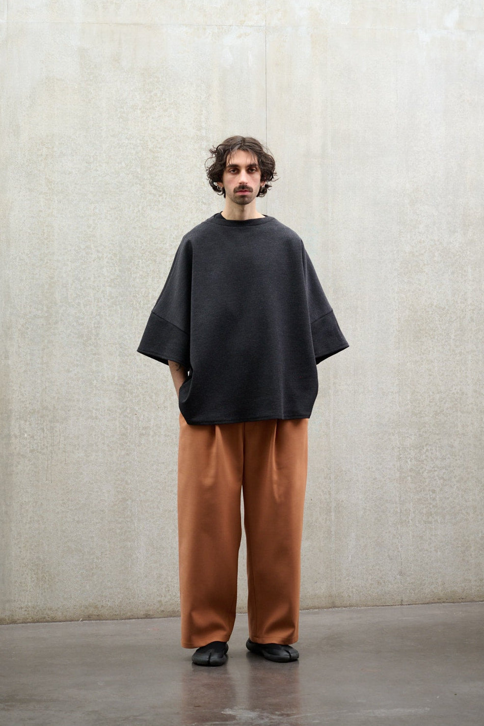 Pantalon droit de la marque Aïdama coupe oversize en laine et coton orange. Porté par un mannequin homme, vu de face.