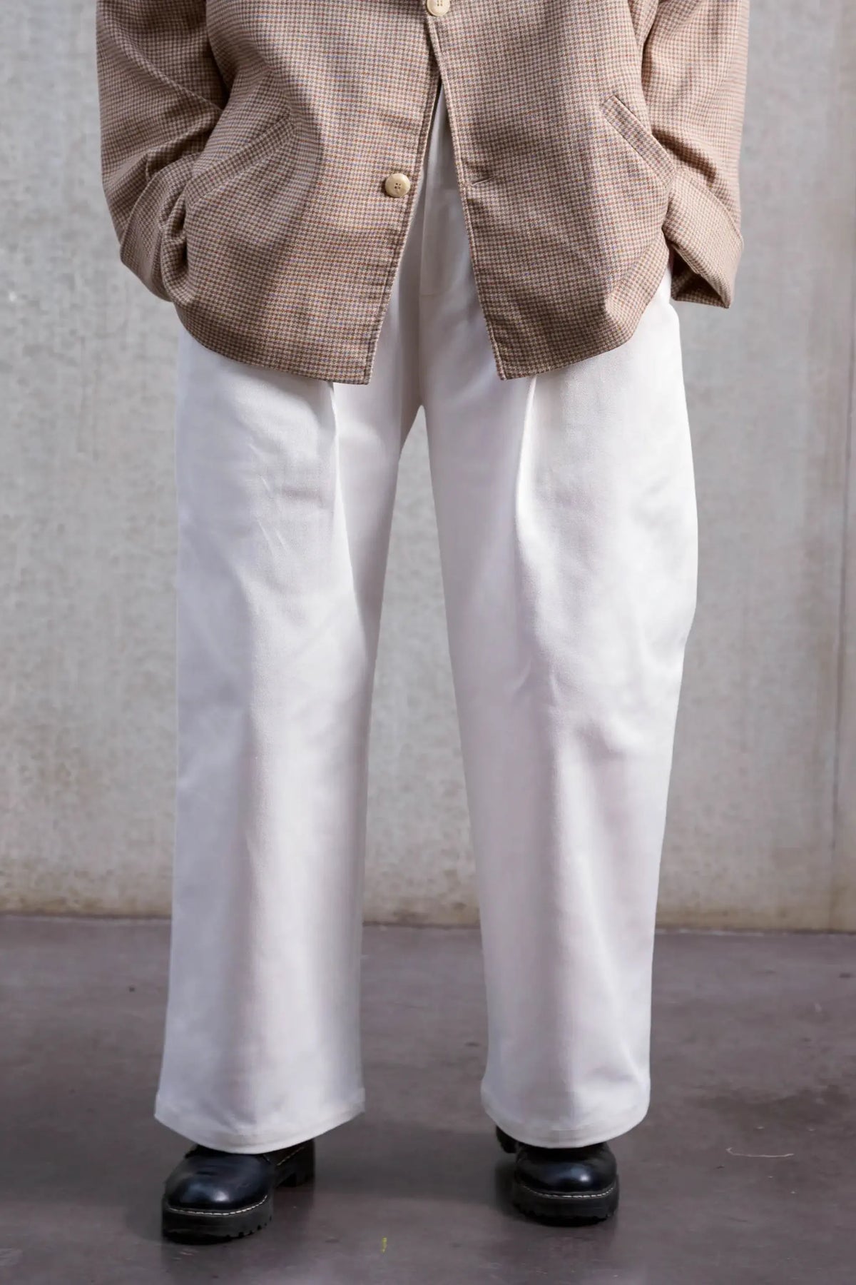 Pantalon droit unisexe de la marque Aïdama, coupe oversize en sergé de coton blanc. Porté par une mannequin femme et vu de face zoomé sur les jambes.
