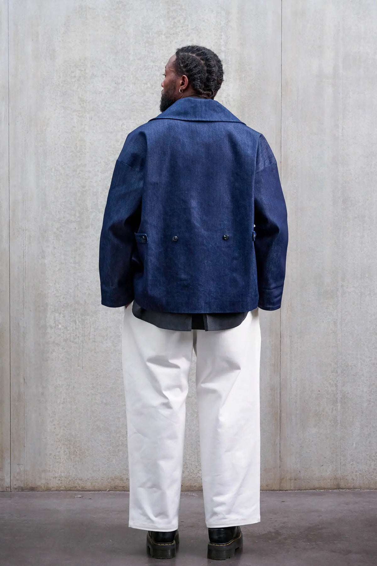 Pantalon droit unisexe de la marque Aïdama, coupe oversize en sergé de coton blanc. Porté par un mannequin homme et vu de dos.