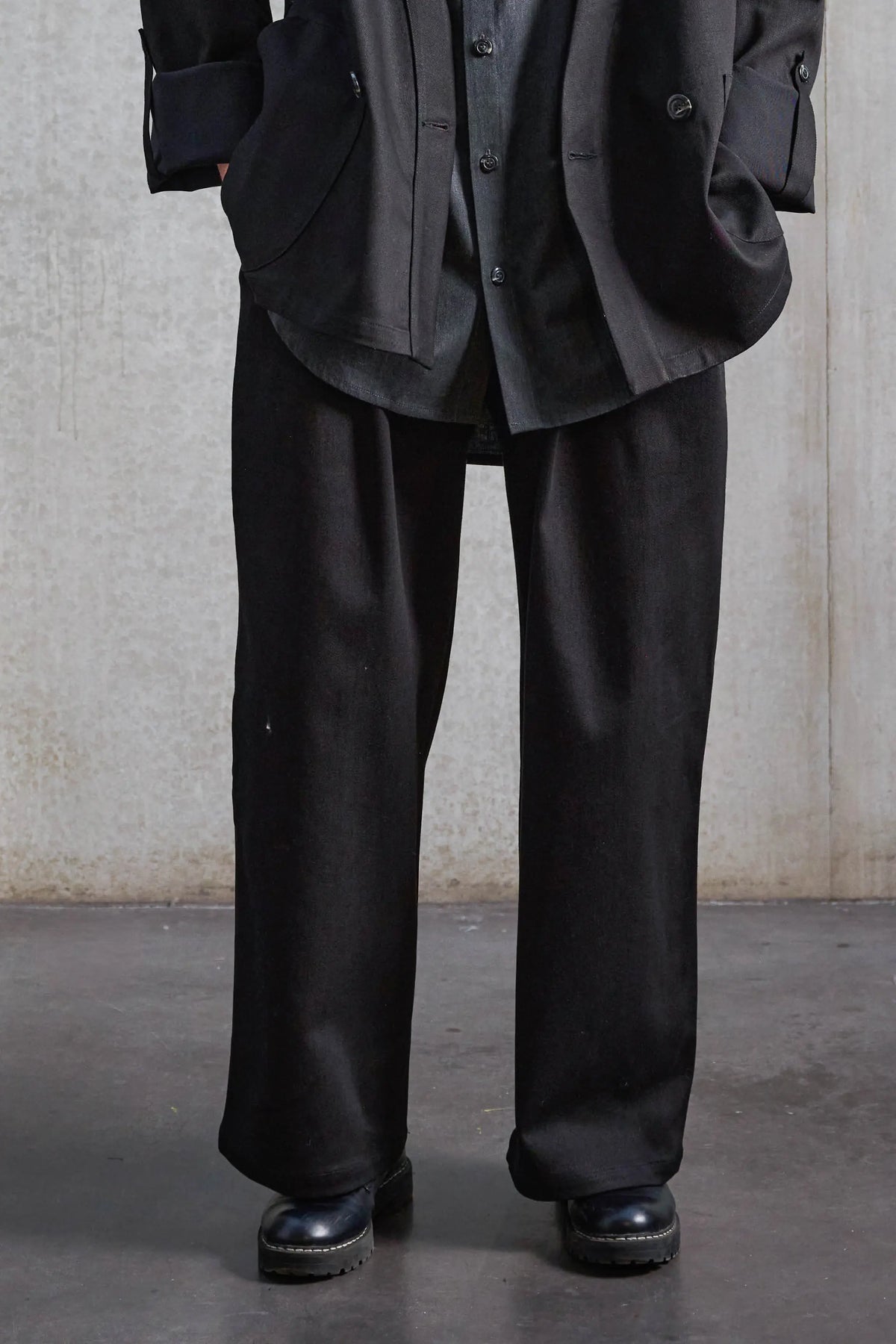 Pantalon droit unisexe de la marque Aïdama, coupe oversize en sergé de coton noir. Porté par une mannequin femme et vu de face zoomé sur les jambes.