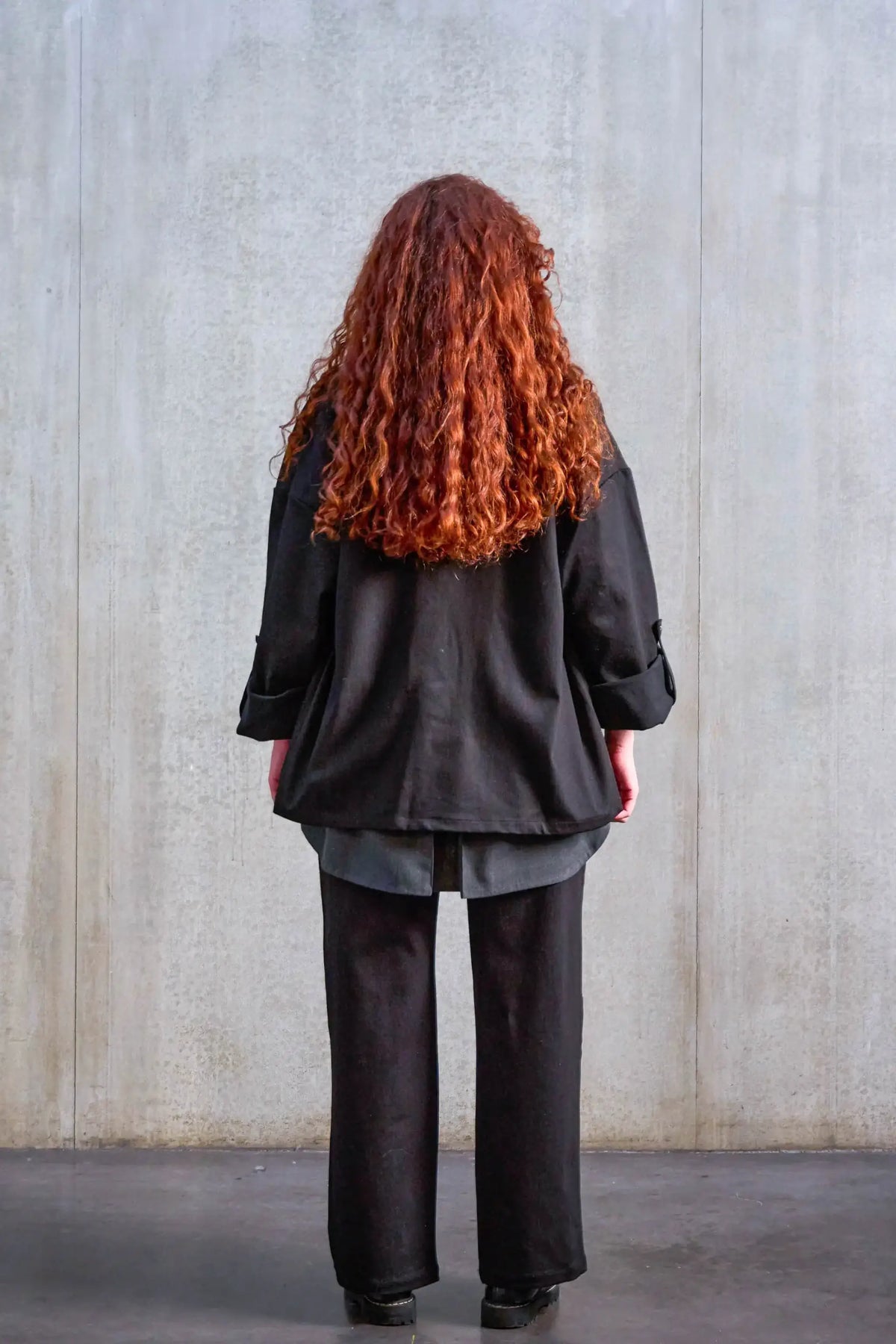 Pantalon droit unisexe de la marque Aïdama, coupe oversize en sergé de coton noir. Porté par une mannequin femme et vu de dos.