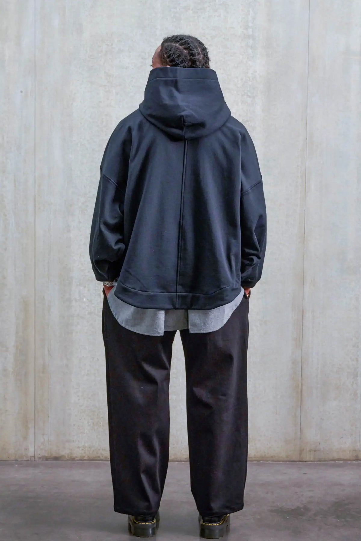 Pantalon droit unisexe de la marque Aïdama, coupe oversize en sergé de coton noir. Porté par un mannequin homme et vu de dos.