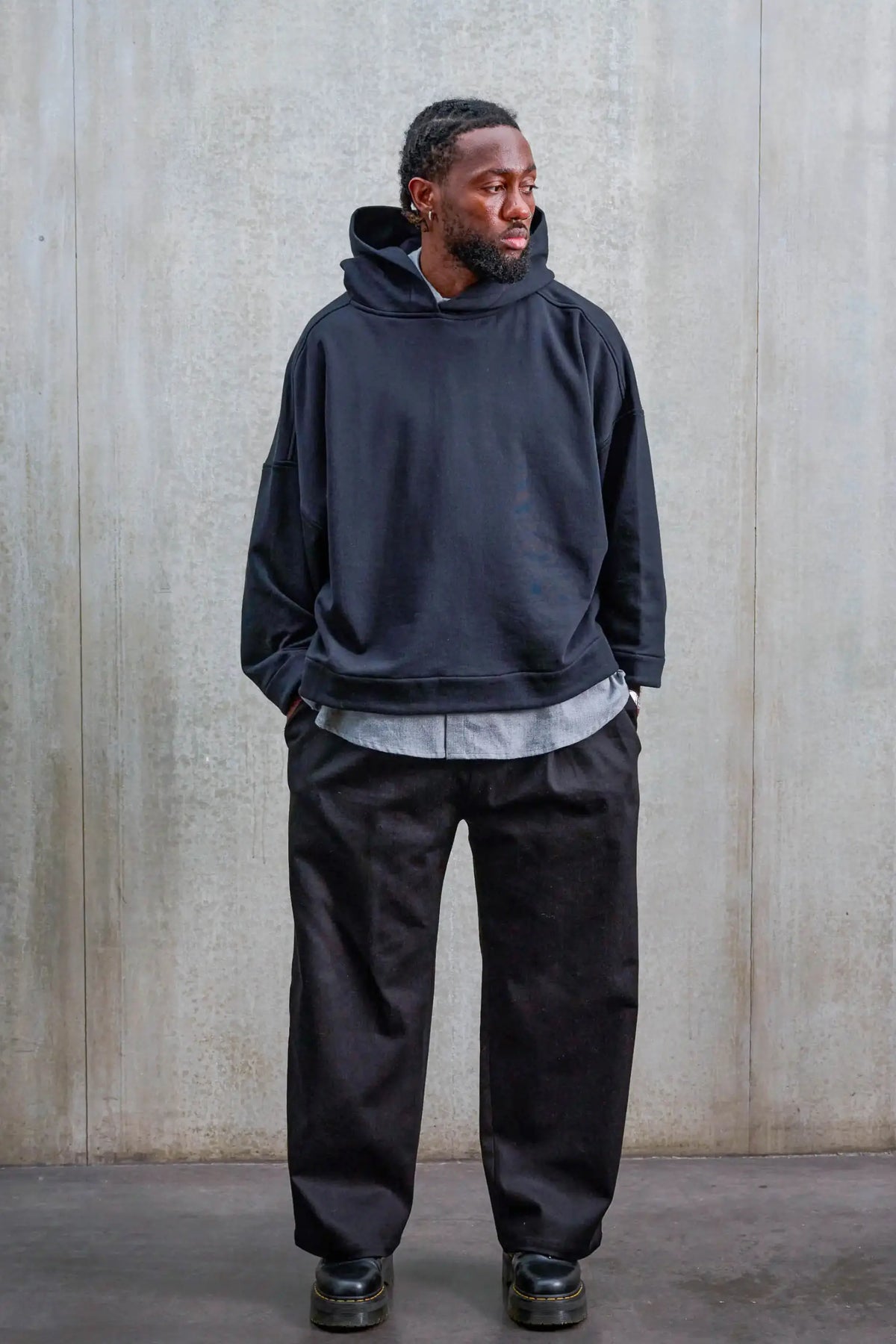 Pantalon droit unisexe de la marque Aïdama, coupe oversize en sergé de coton noir. Porté par un mannequin homme et vu de face.