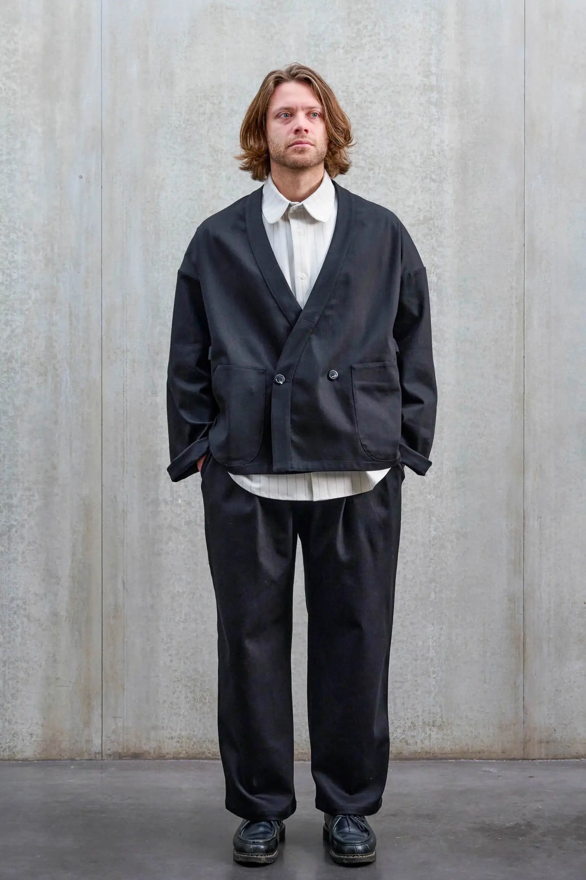 Pantalon droit unisexe de la marque Aïdama, coupe oversize en sergé de coton noir. Porté par un mannequin homme et vu de face.