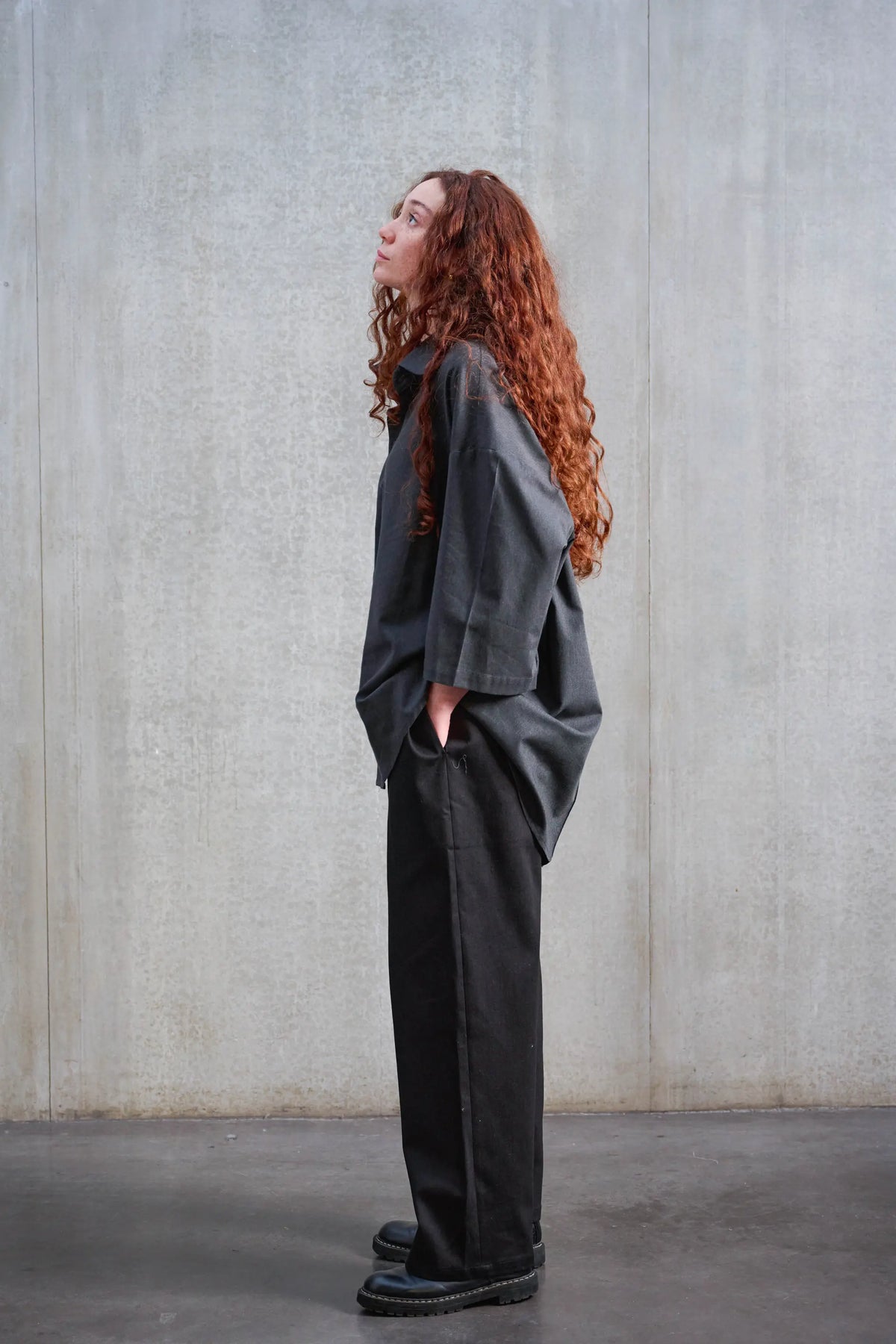 Pantalon droit unisexe de la marque Aïdama, coupe oversize en sergé de coton noir. Porté par une mannequin femme et vu de profil.