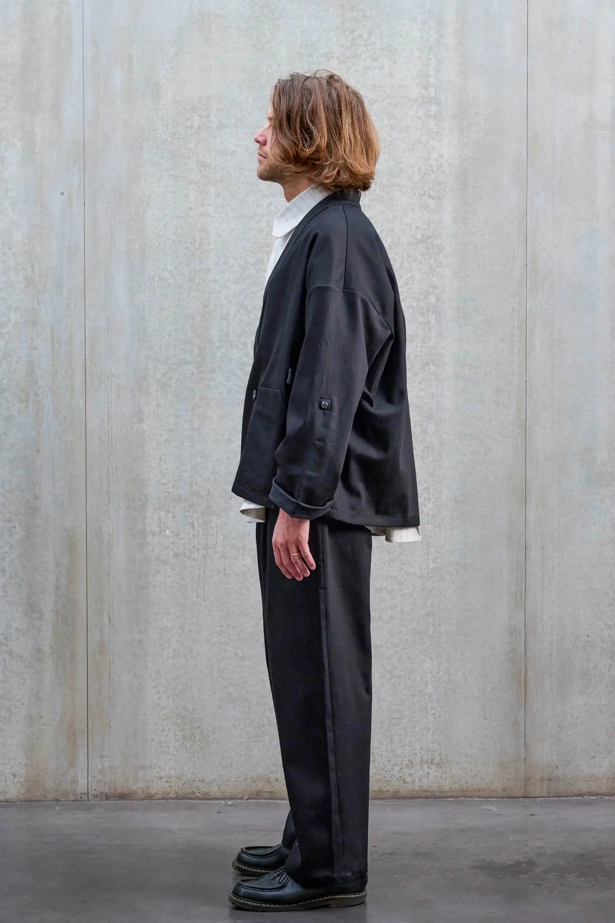 Pantalon droit unisexe de la marque Aïdama, coupe oversize en sergé de coton noir. Porté par un mannequin homme et vu de profil.