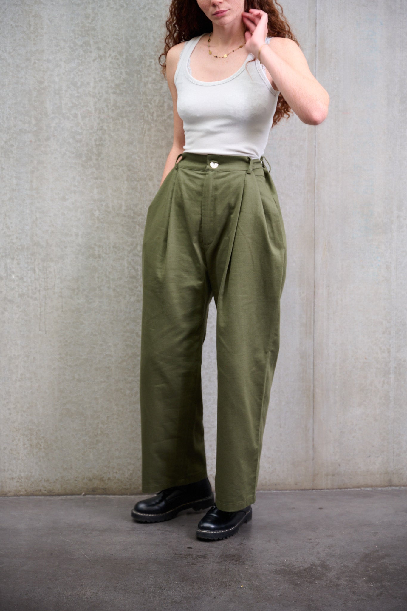 Pantalon droit à coupe ample en coton vert avec sangles de réglages de la marque Aïdama. Porté taille haute par une mannequin femme et vu de face.