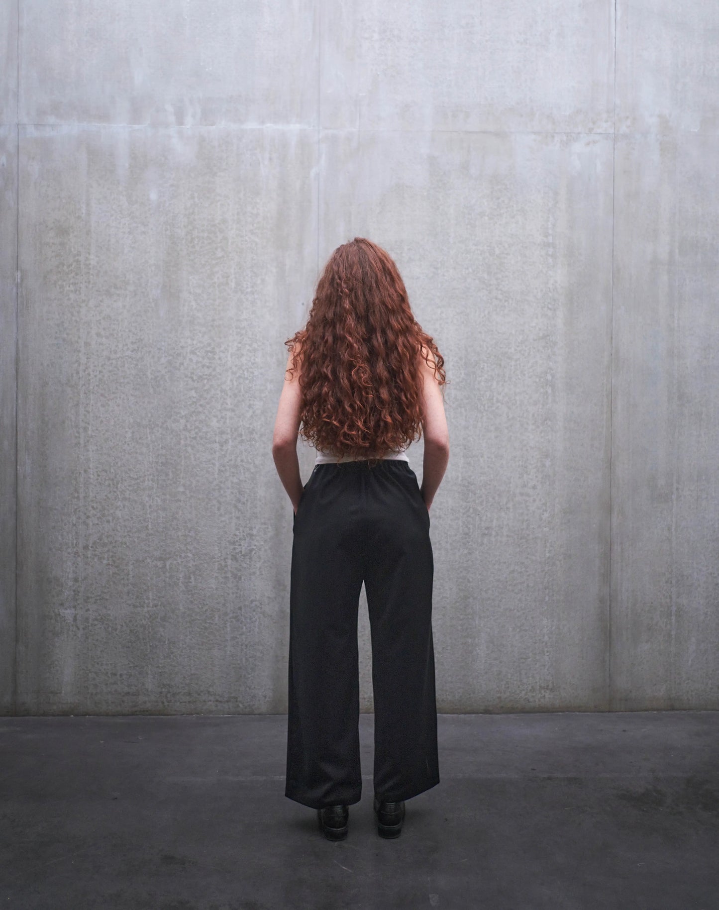 Pantalon droit Aïdama, coupe oversize en laine froide noire. Porté par une mannequin femme et vu de dos.