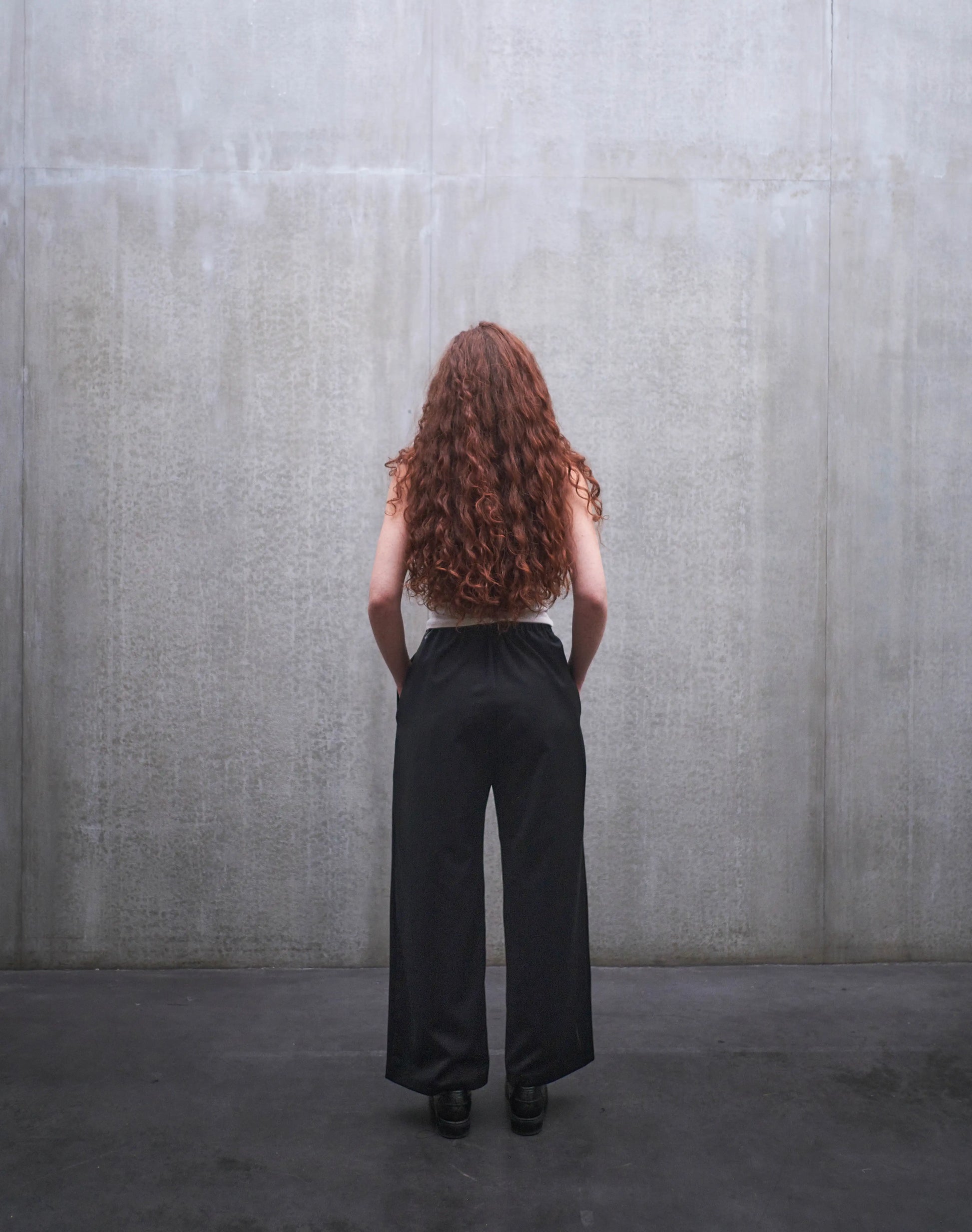 Pantalon droit Aïdama, coupe oversize en laine froide noire. Porté par une mannequin femme et vu de dos.